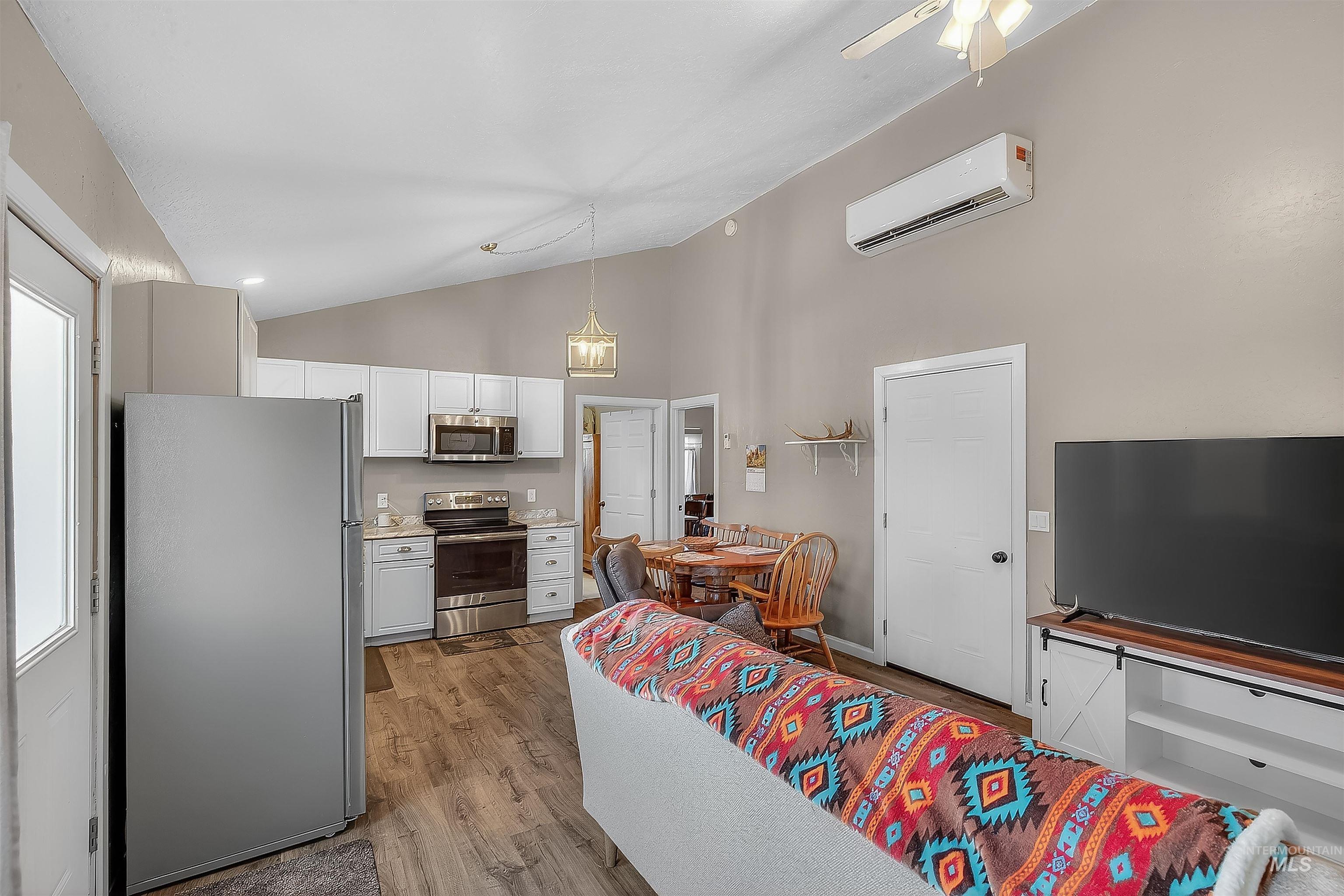 Kitchen featuring stainless steel appliances, light countertops, light wood-type flooring, white cabinets, and pendant lighting