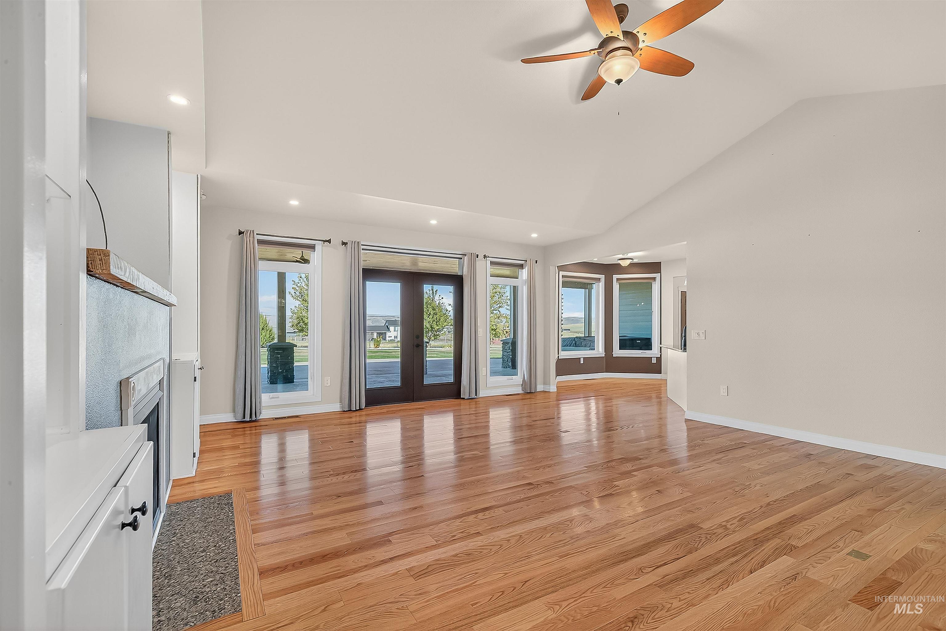 Unfurnished living room with light wood-style flooring, french doors, ceiling fan, recessed lighting, and vaulted ceiling