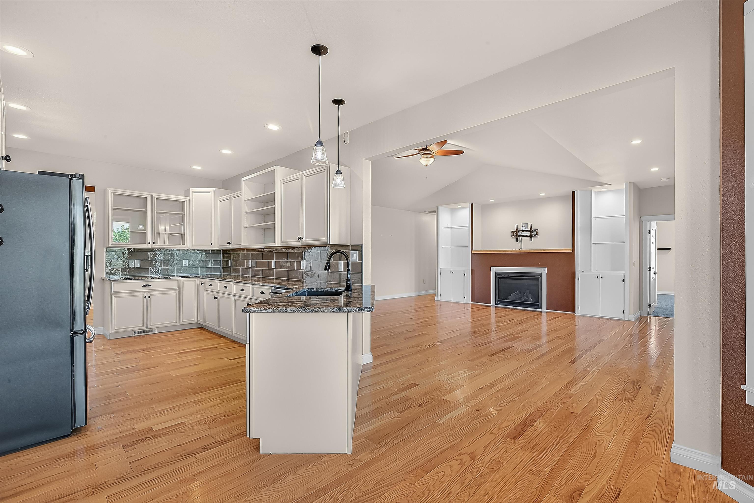 Kitchen featuring open shelves, freestanding refrigerator, white cabinets, dark stone countertops, and light wood-style floors
