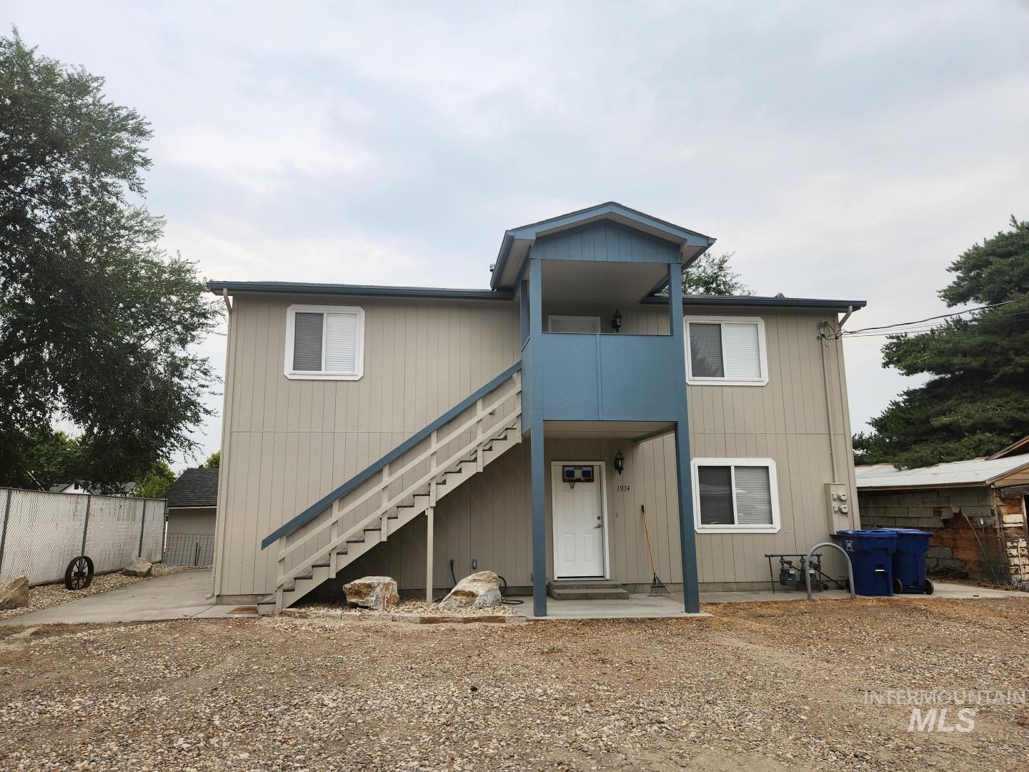 View of front of property with stairs, a patio area, and a balcony
