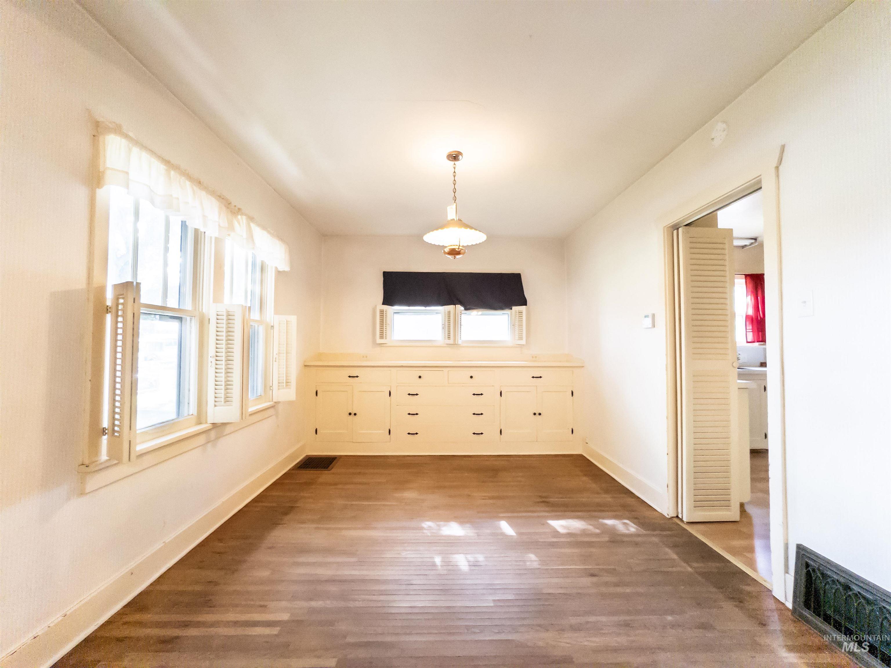 Unfurnished dining area featuring wood finished floors and baseboards