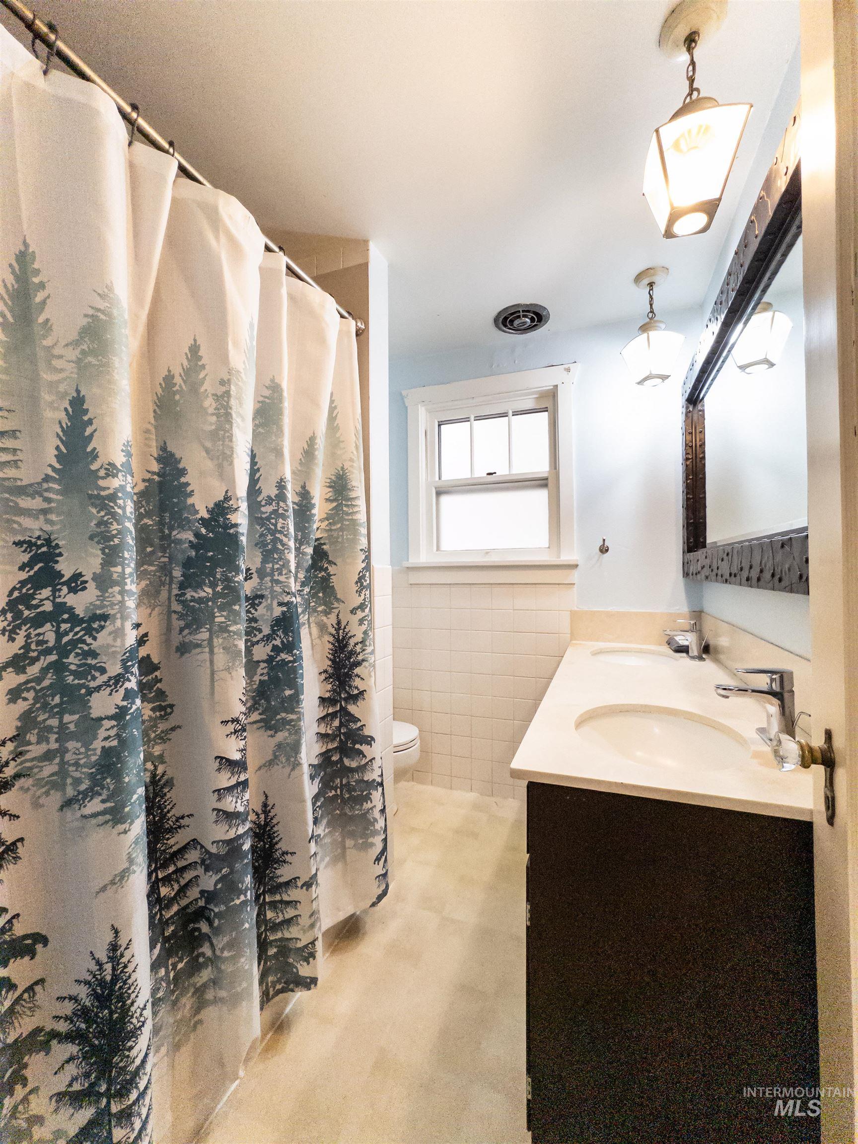 Bathroom with tile walls, vanity, and a shower with shower curtain