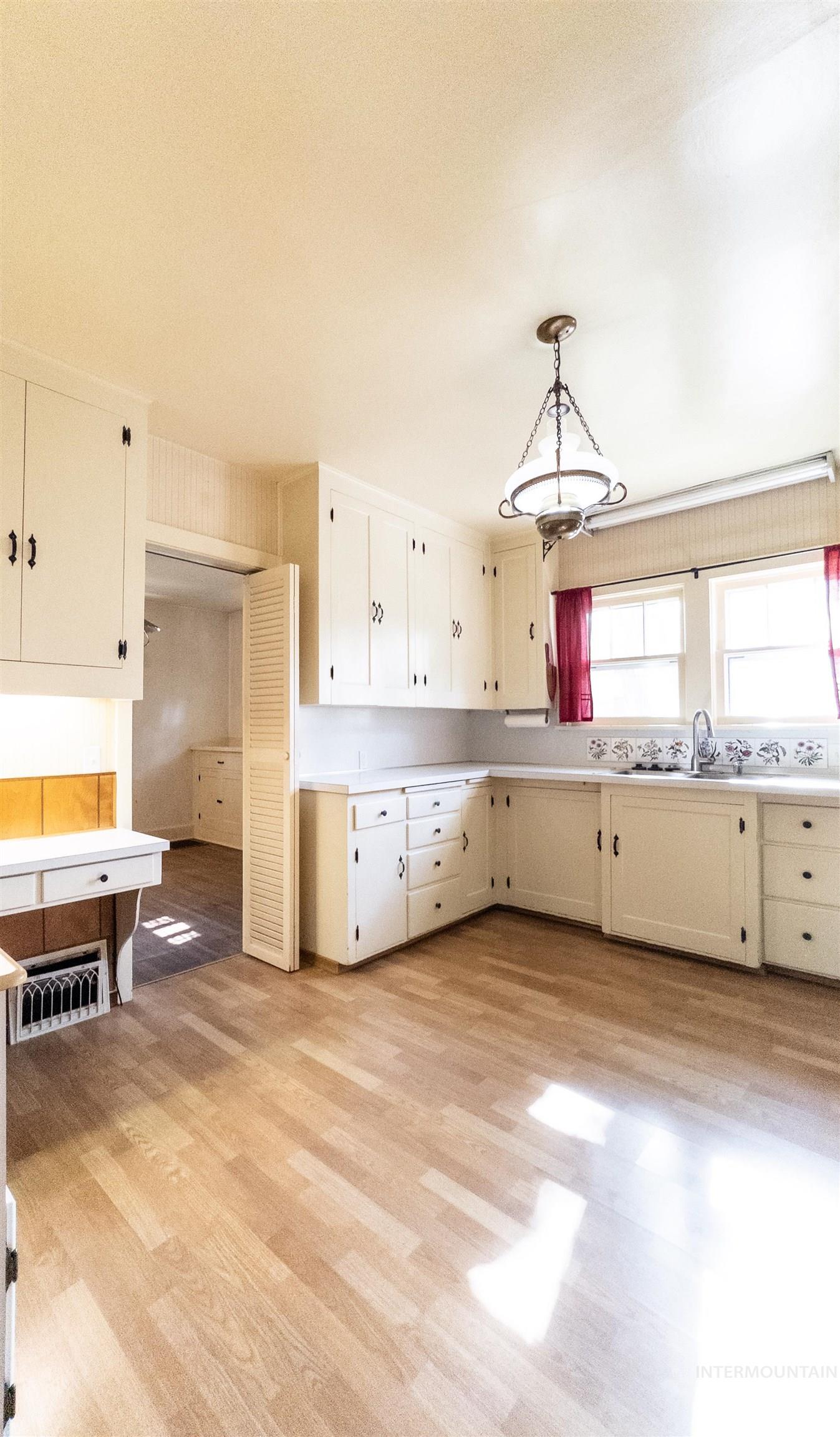 Kitchen featuring light countertops, light wood-style floors, white cabinets, and decorative light fixtures