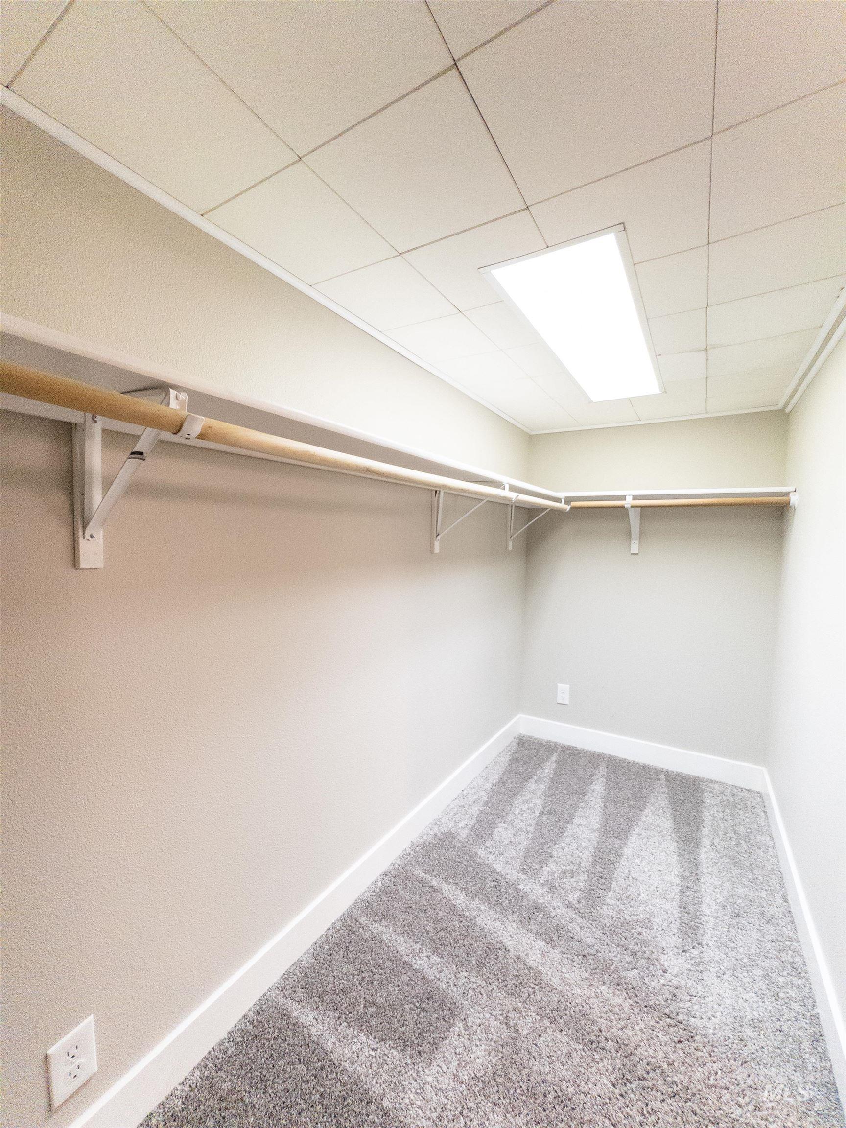 Spacious closet with light colored carpet and a paneled ceiling