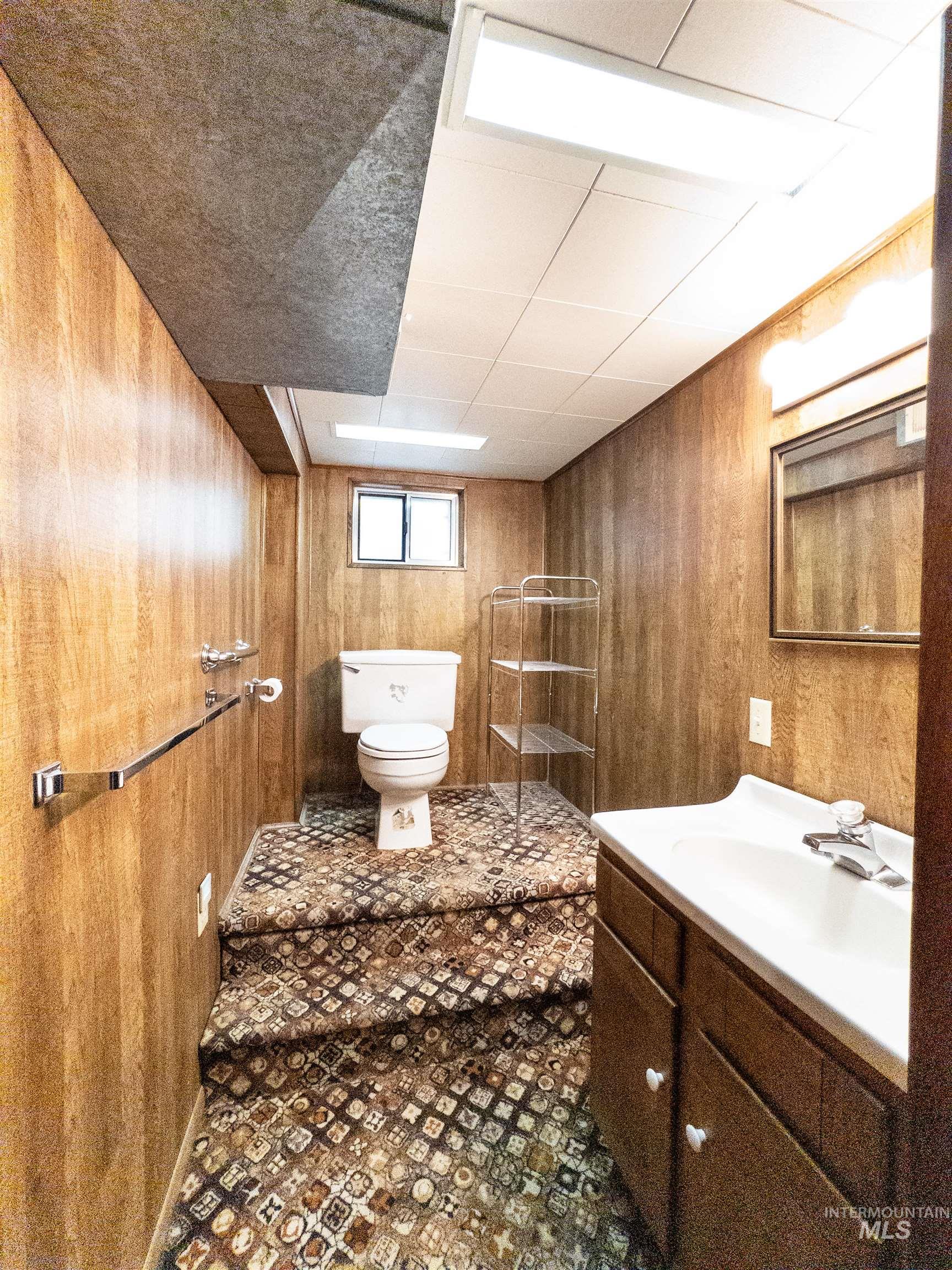 Bathroom with wooden walls, vanity, and a drop ceiling