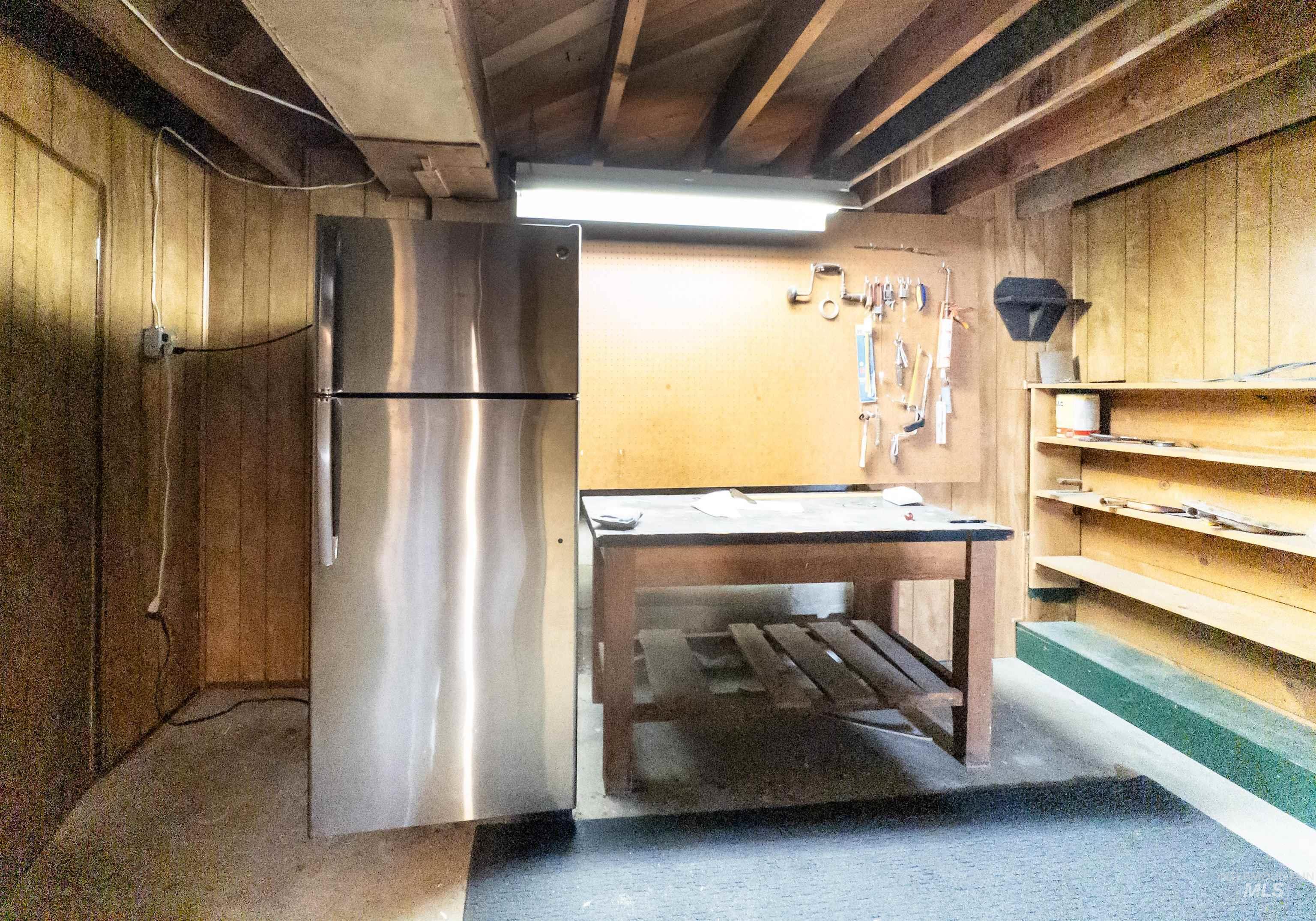 Basement with wood walls and freestanding refrigerator
