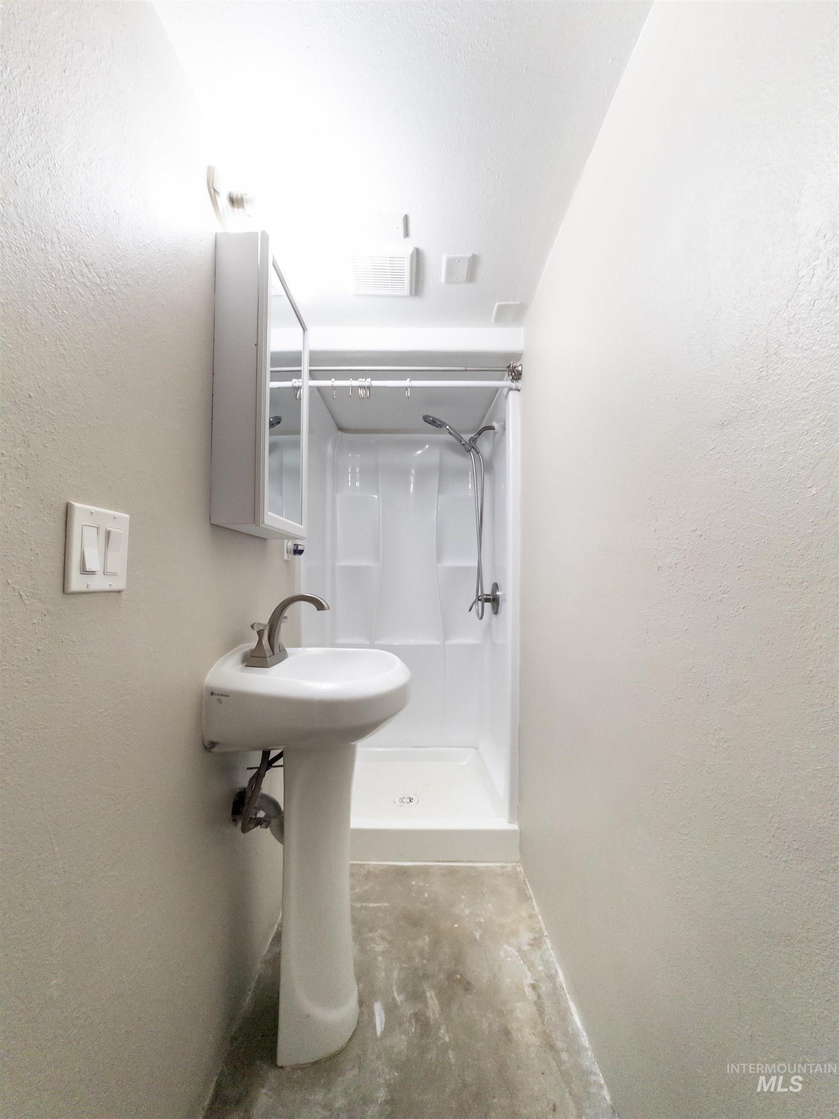 Full bathroom with a shower stall and a textured wall