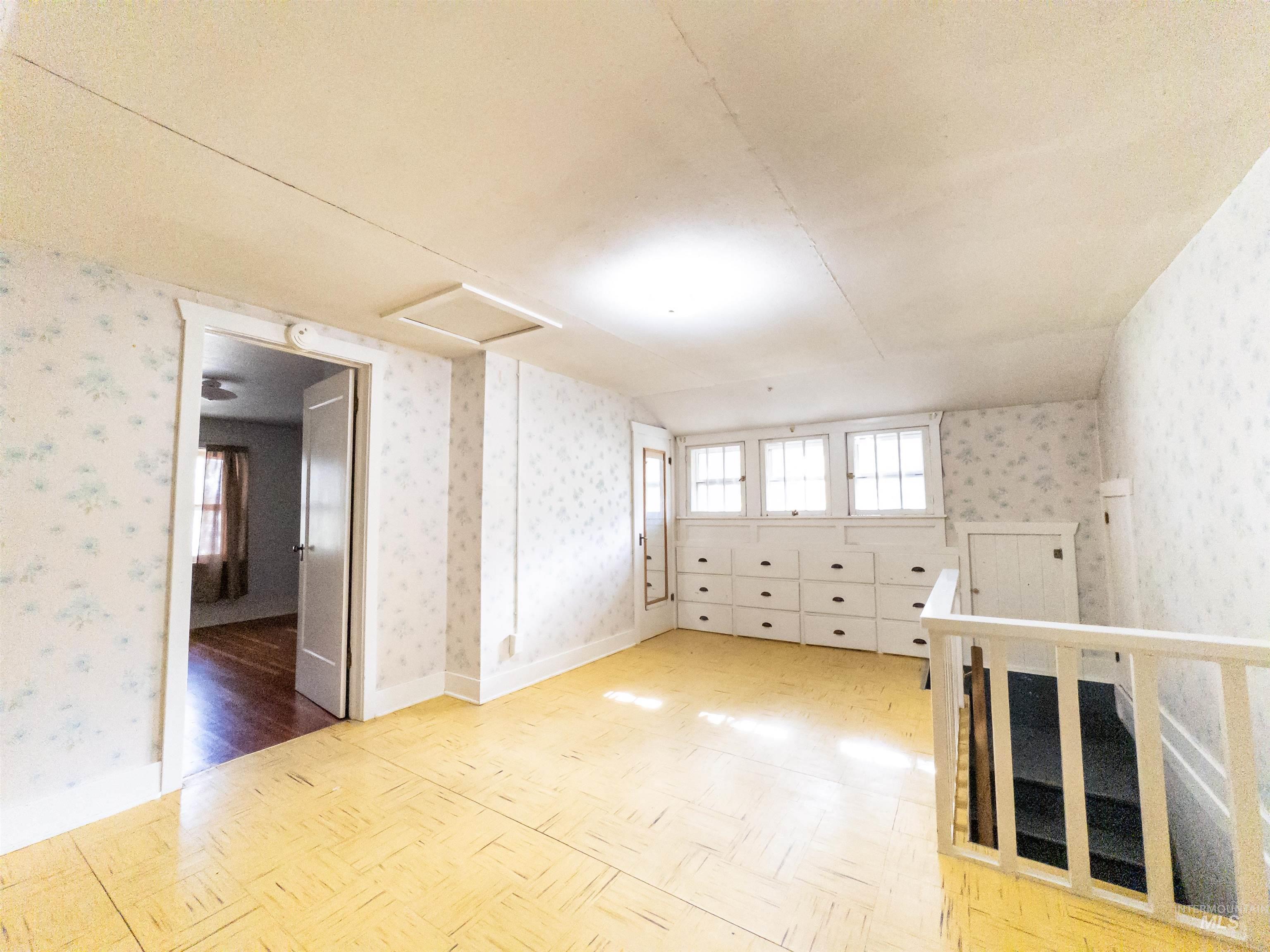 Bonus room with wallpapered walls, attic access, and parquet floors