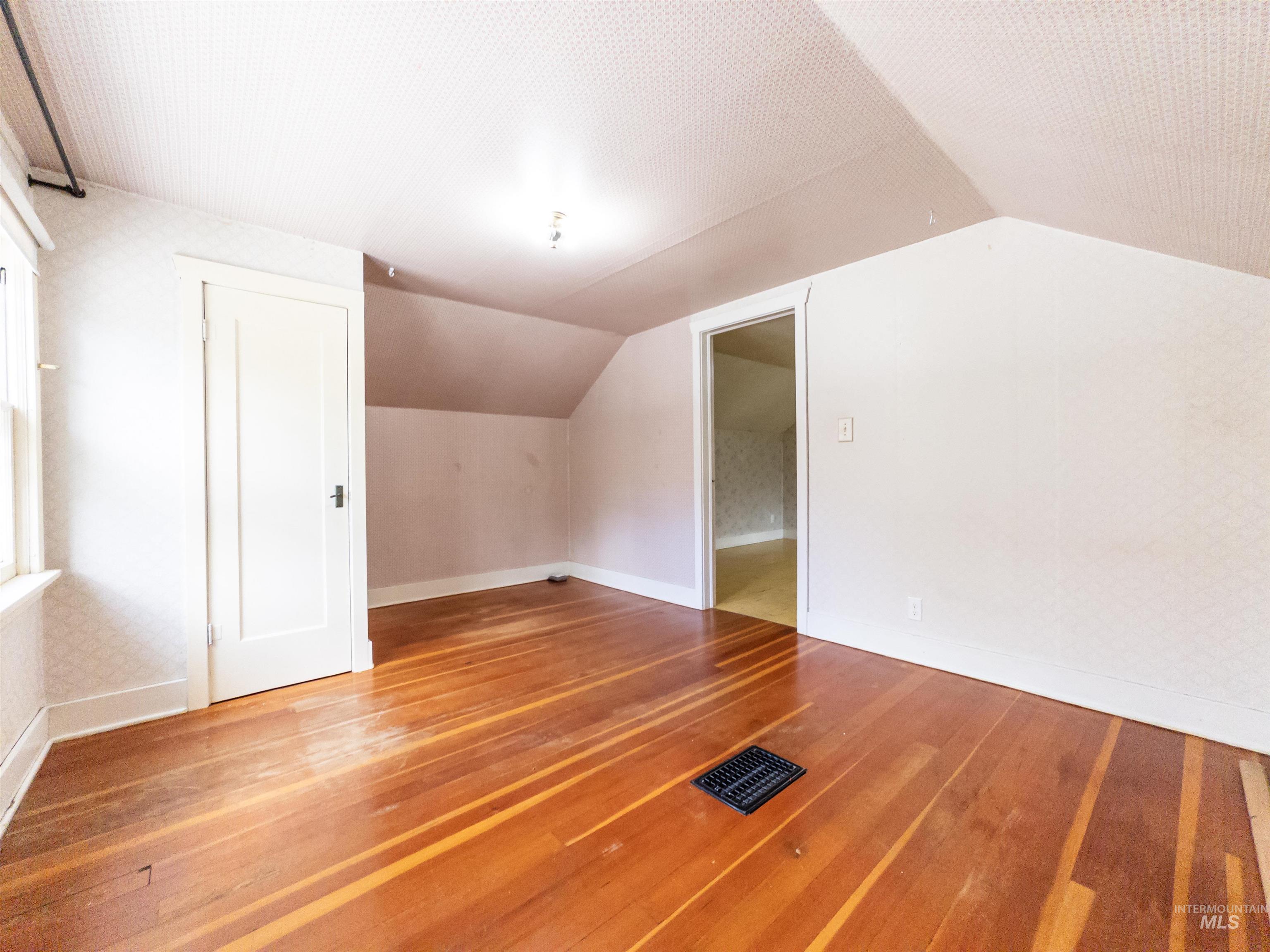 Additional living space featuring lofted ceiling and light wood-style flooring
