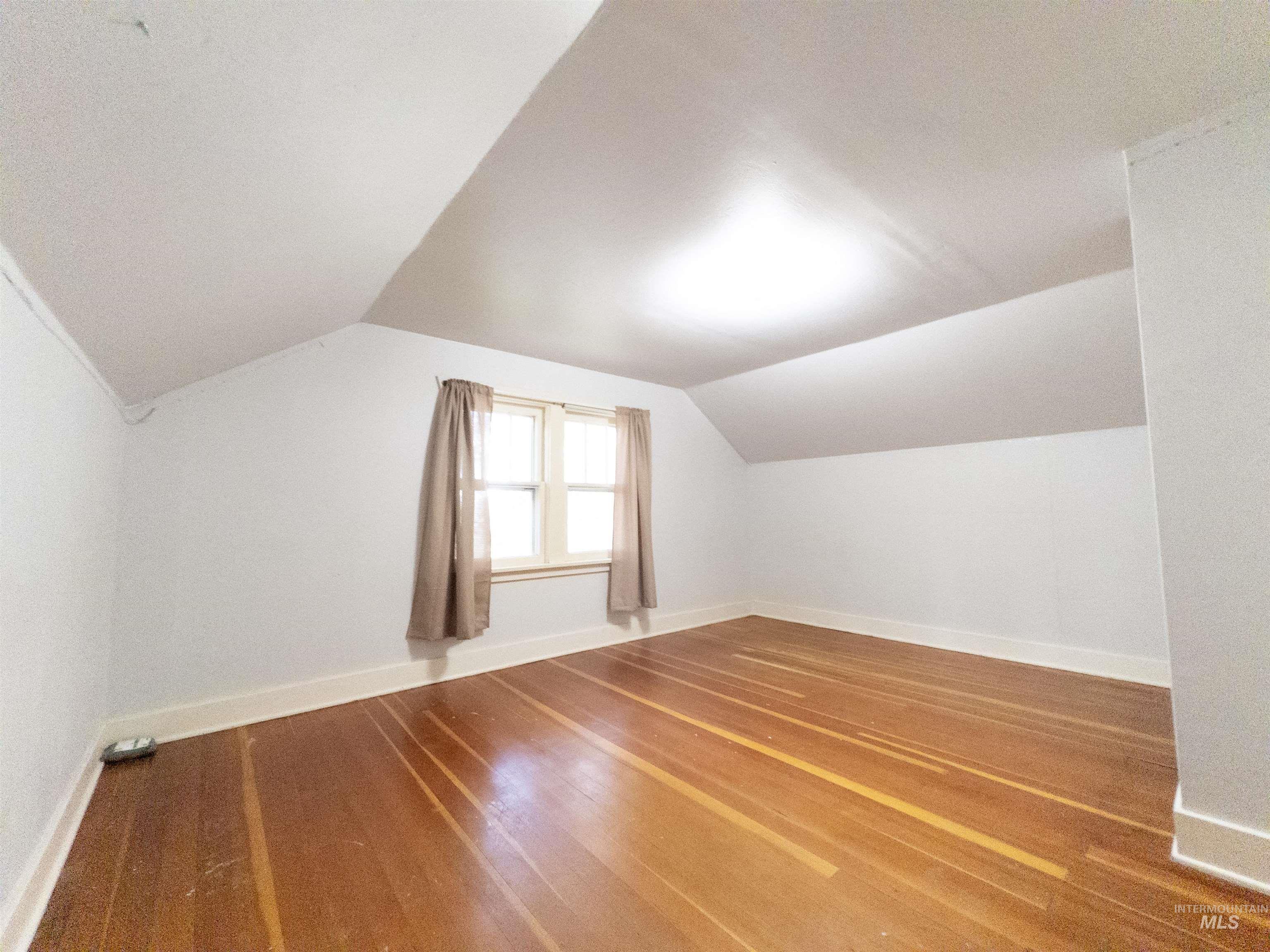 Additional living space with wood finished floors and lofted ceiling