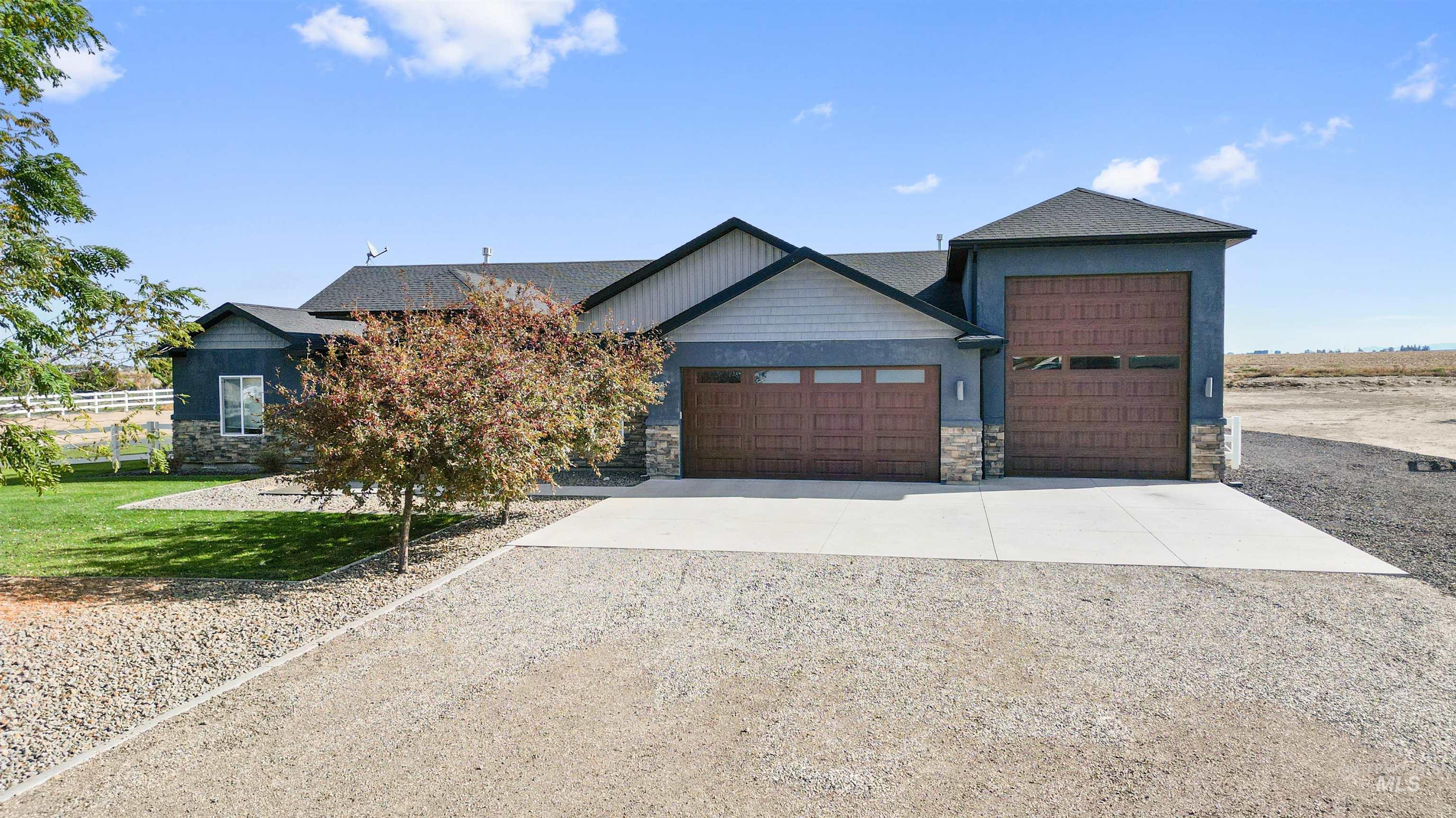 View of front of house featuring driveway, stone siding, a garage, and a front lawn