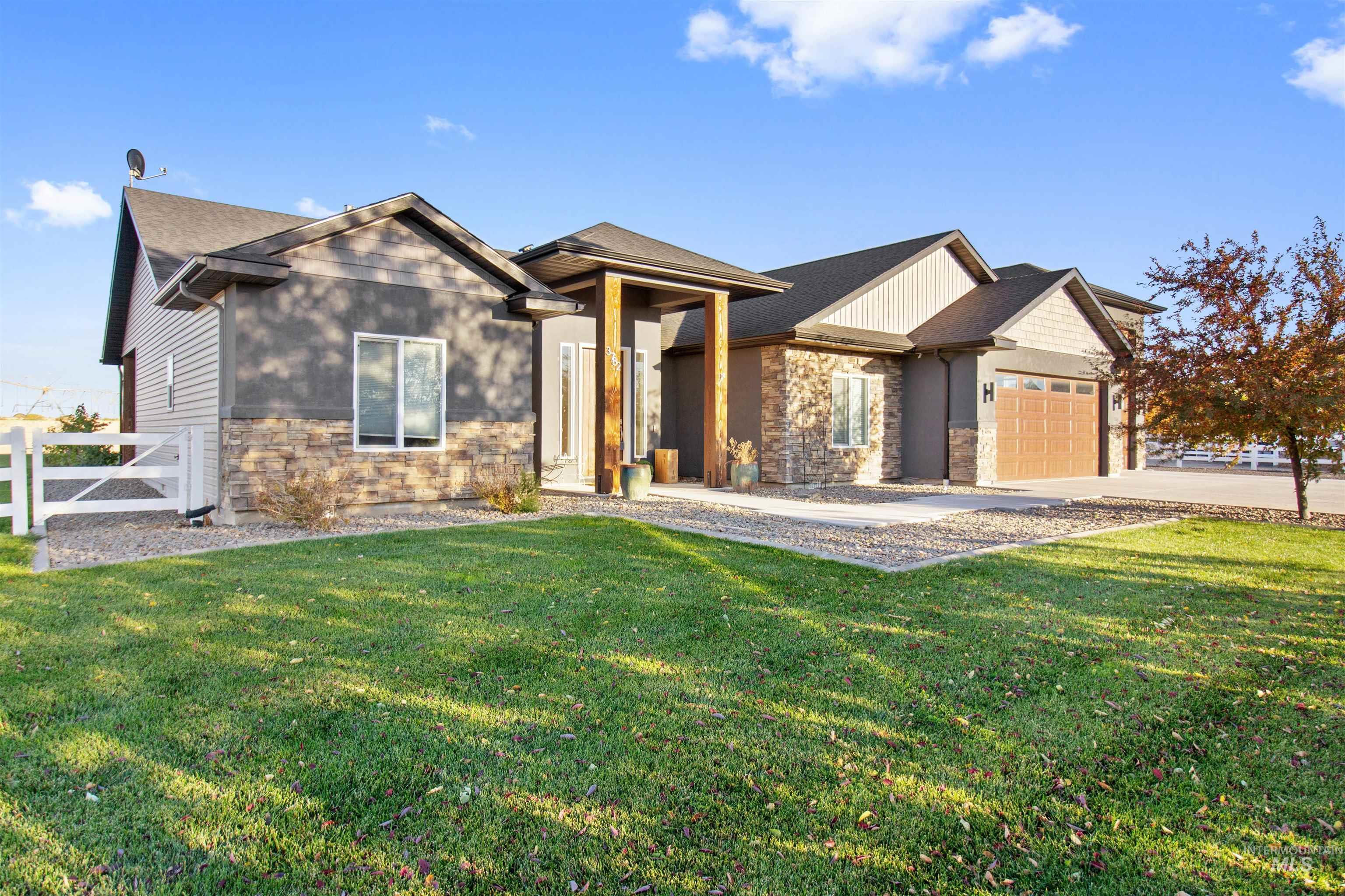 View of front of property featuring a garage, stone siding, driveway, and roof with shingles