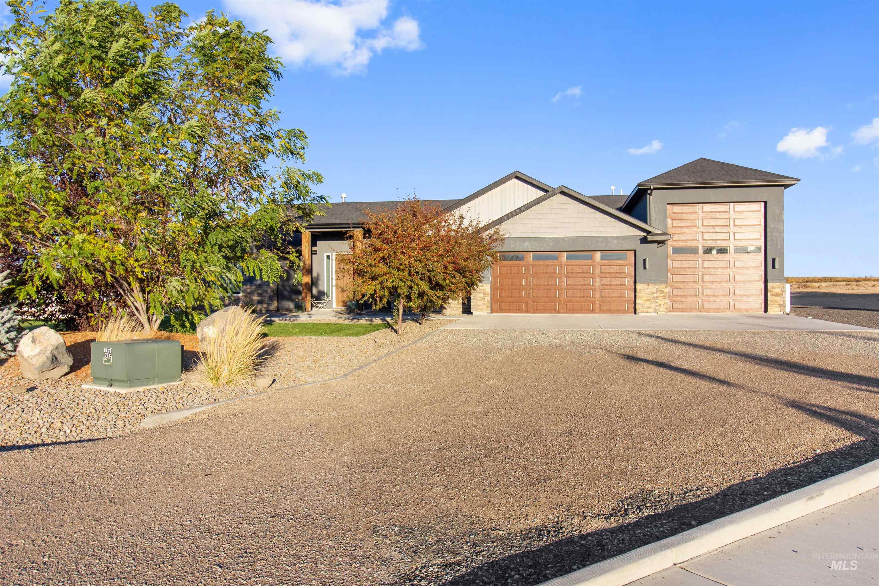 Ranch-style home featuring driveway, an attached garage, and stone siding