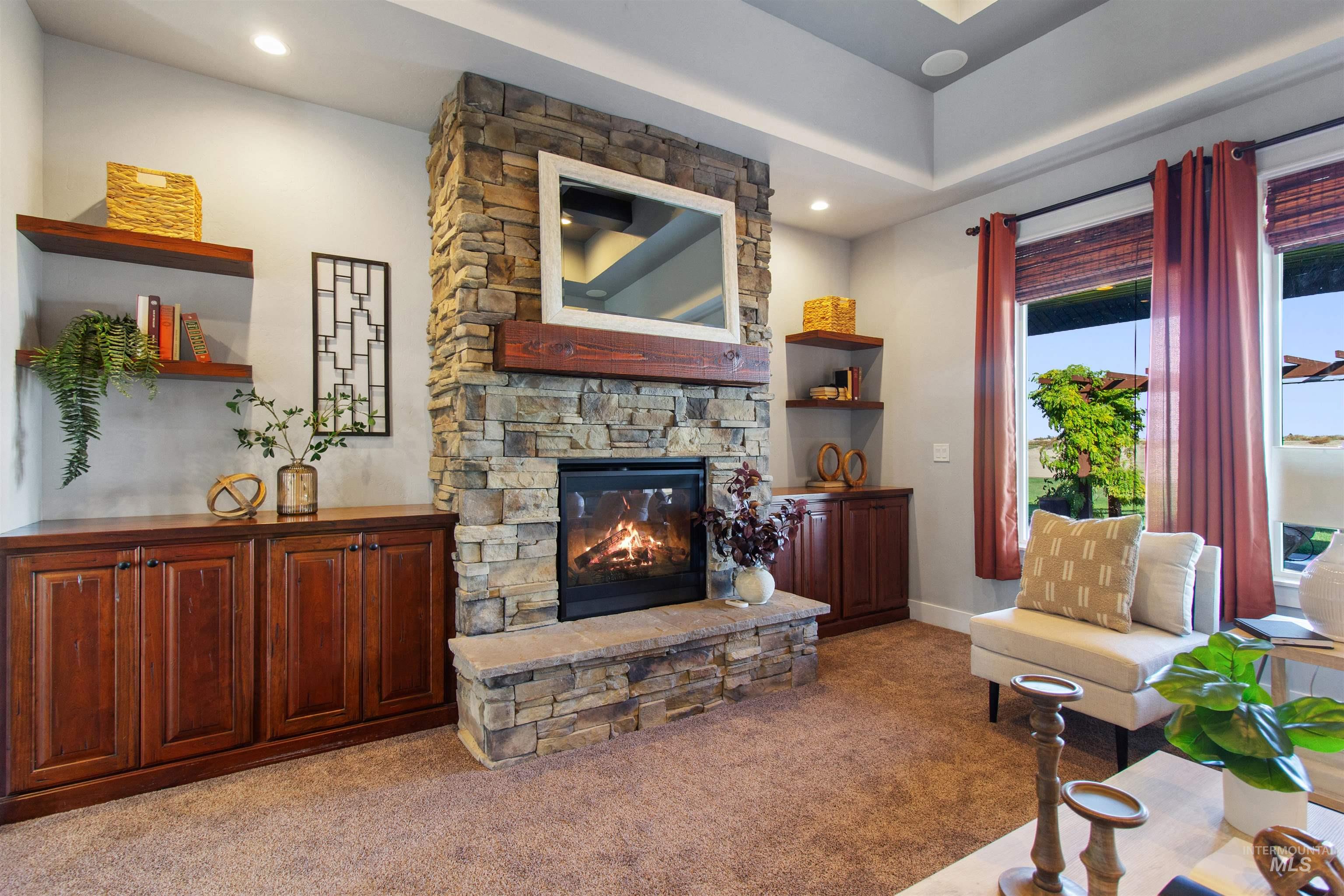 Living area featuring carpet floors, a stone fireplace, and recessed lighting