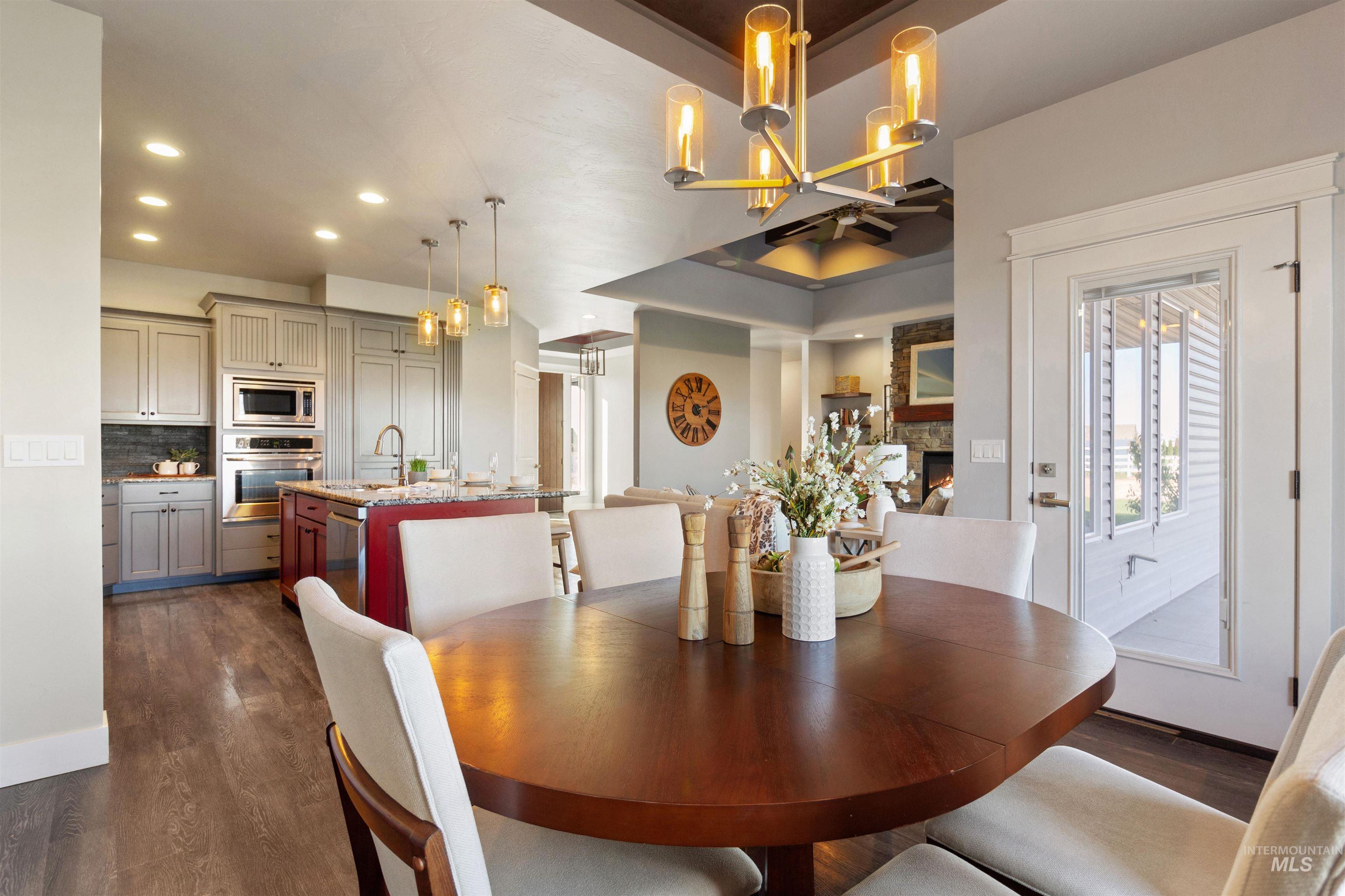 Dining area with a stone fireplace, dark wood-style floors, recessed lighting, and a chandelier