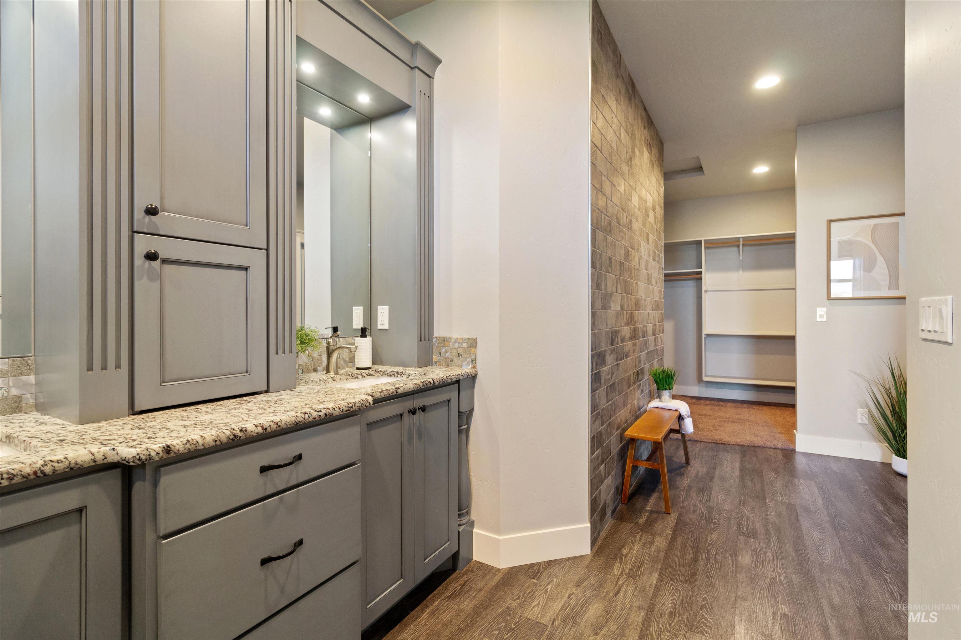 Bathroom featuring a walk in closet, dark wood-style flooring, double vanity, and recessed lighting
