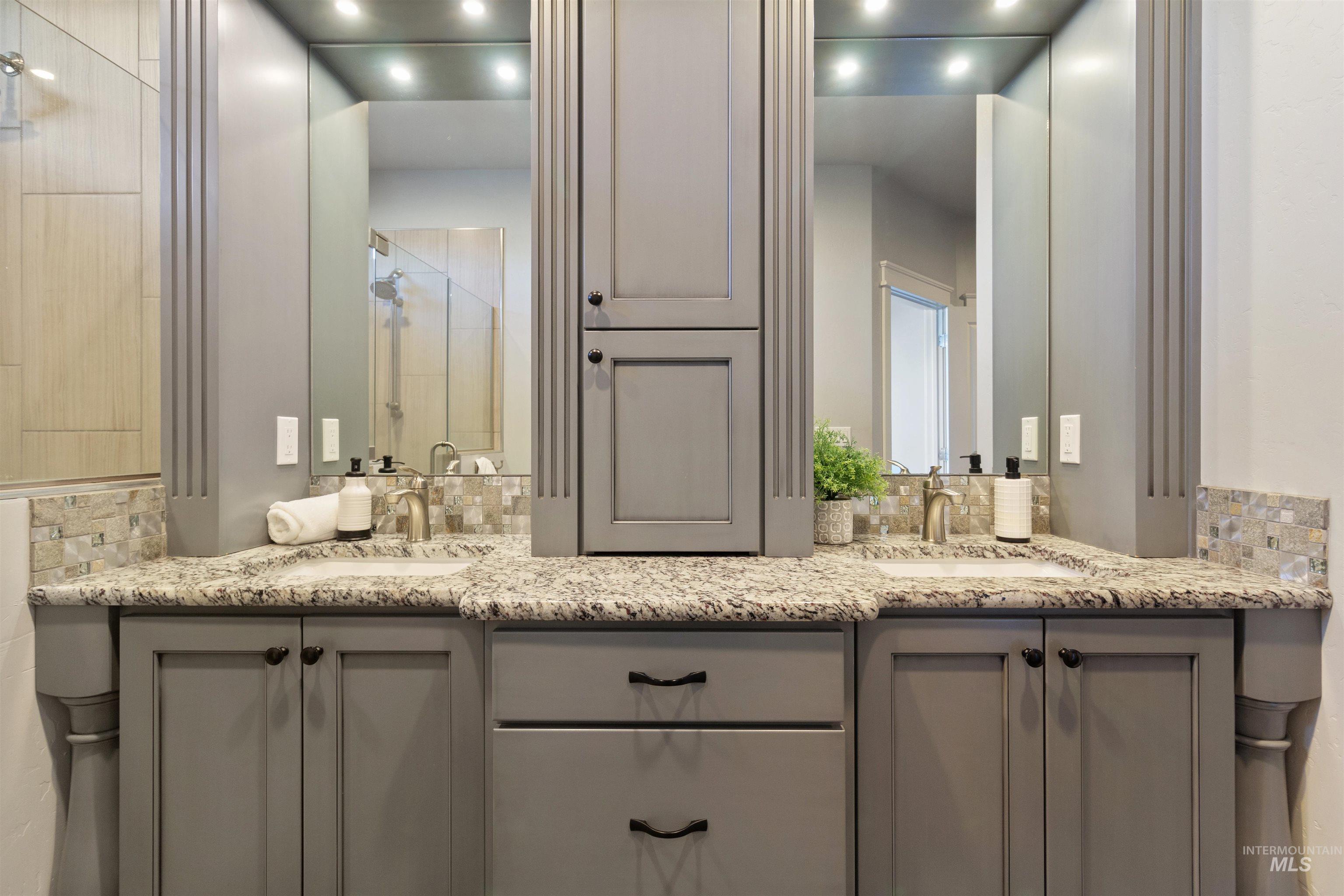 Bathroom featuring double vanity, backsplash, and a shower stall