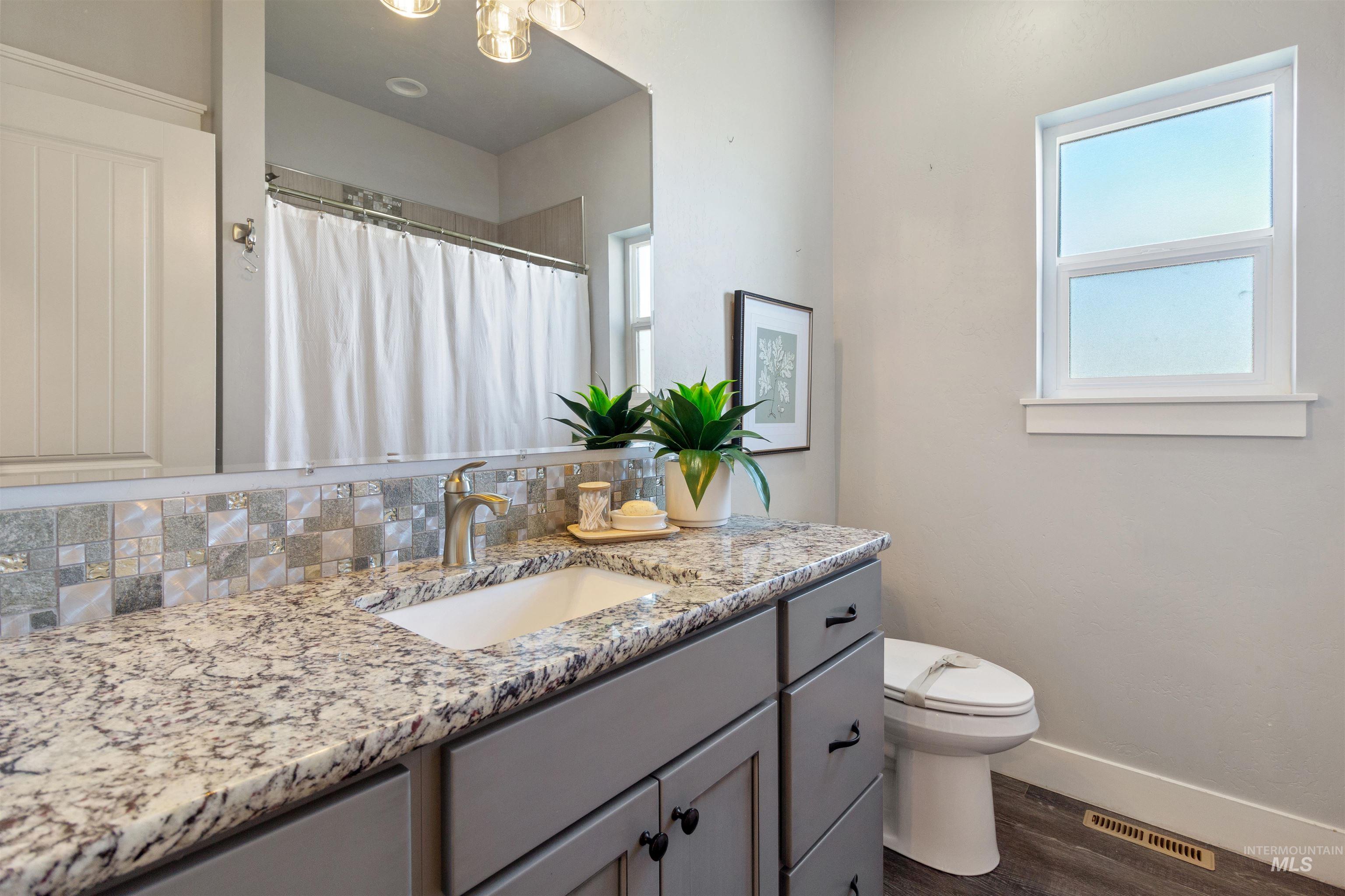 Bathroom featuring dark wood-type flooring, a shower with shower curtain, vanity, and backsplash