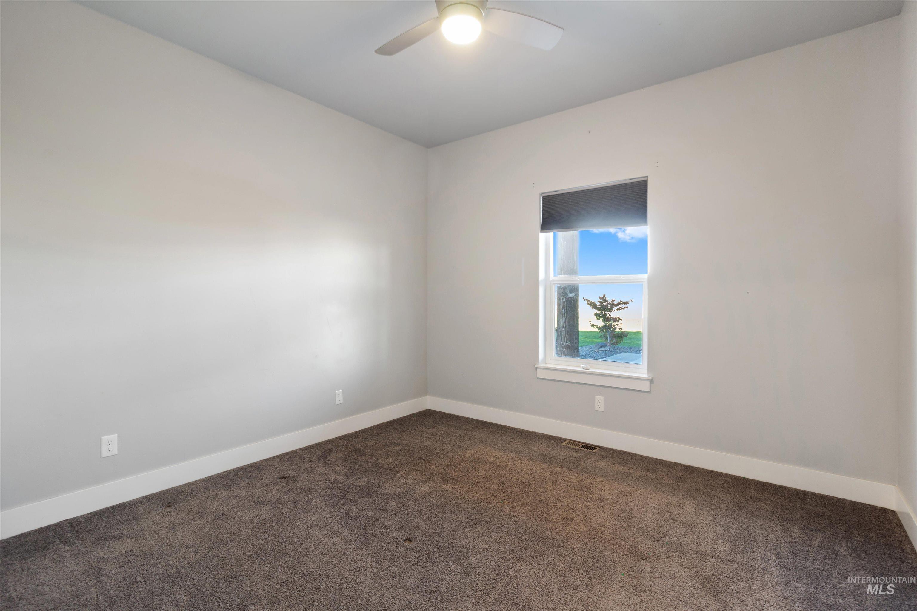 Carpeted spare room featuring baseboards and a ceiling fan