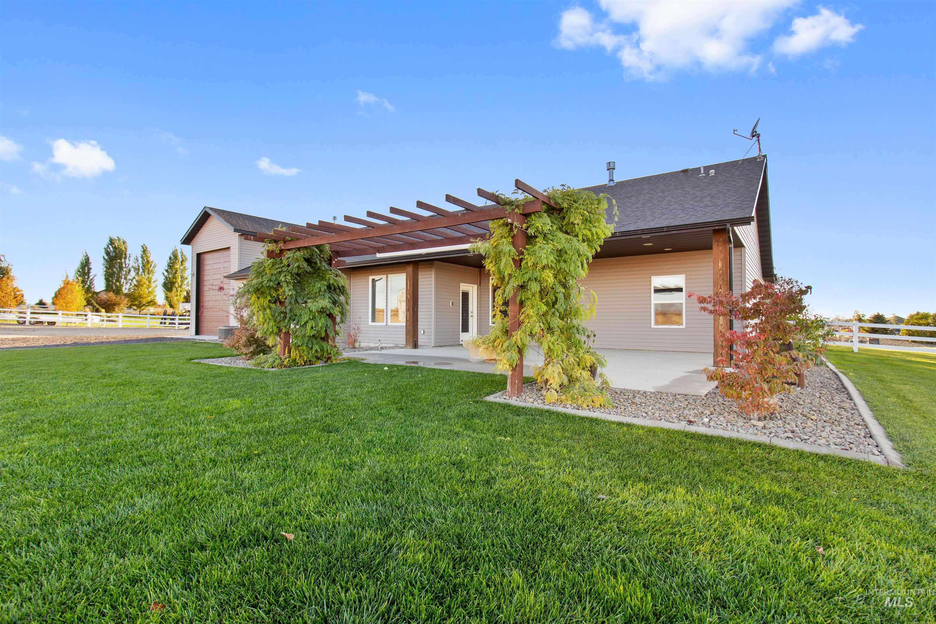 Rear view of property featuring a pergola, a patio, an attached garage, and roof with shingles