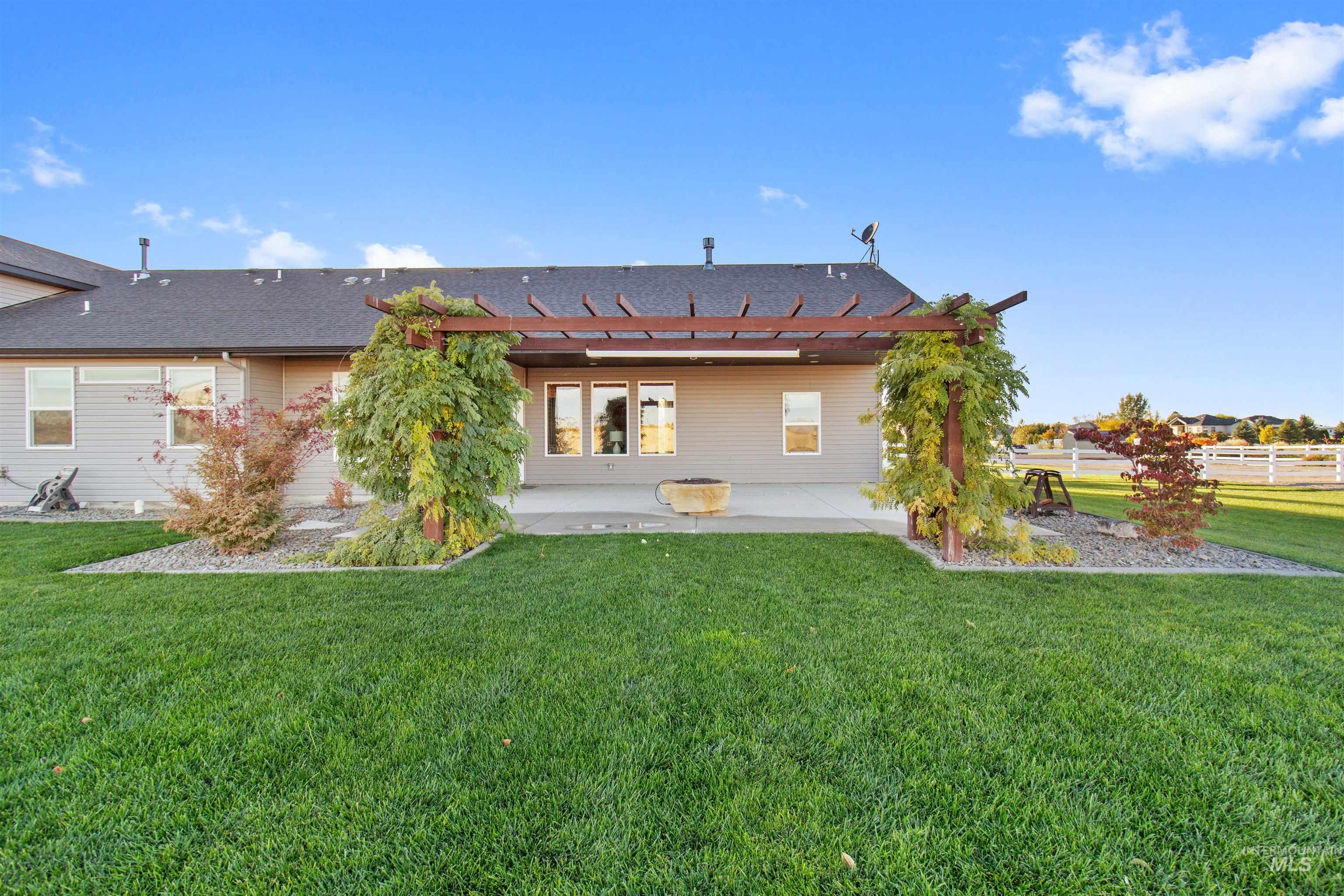 Rear view of property featuring roof with shingles, a pergola, and a patio area