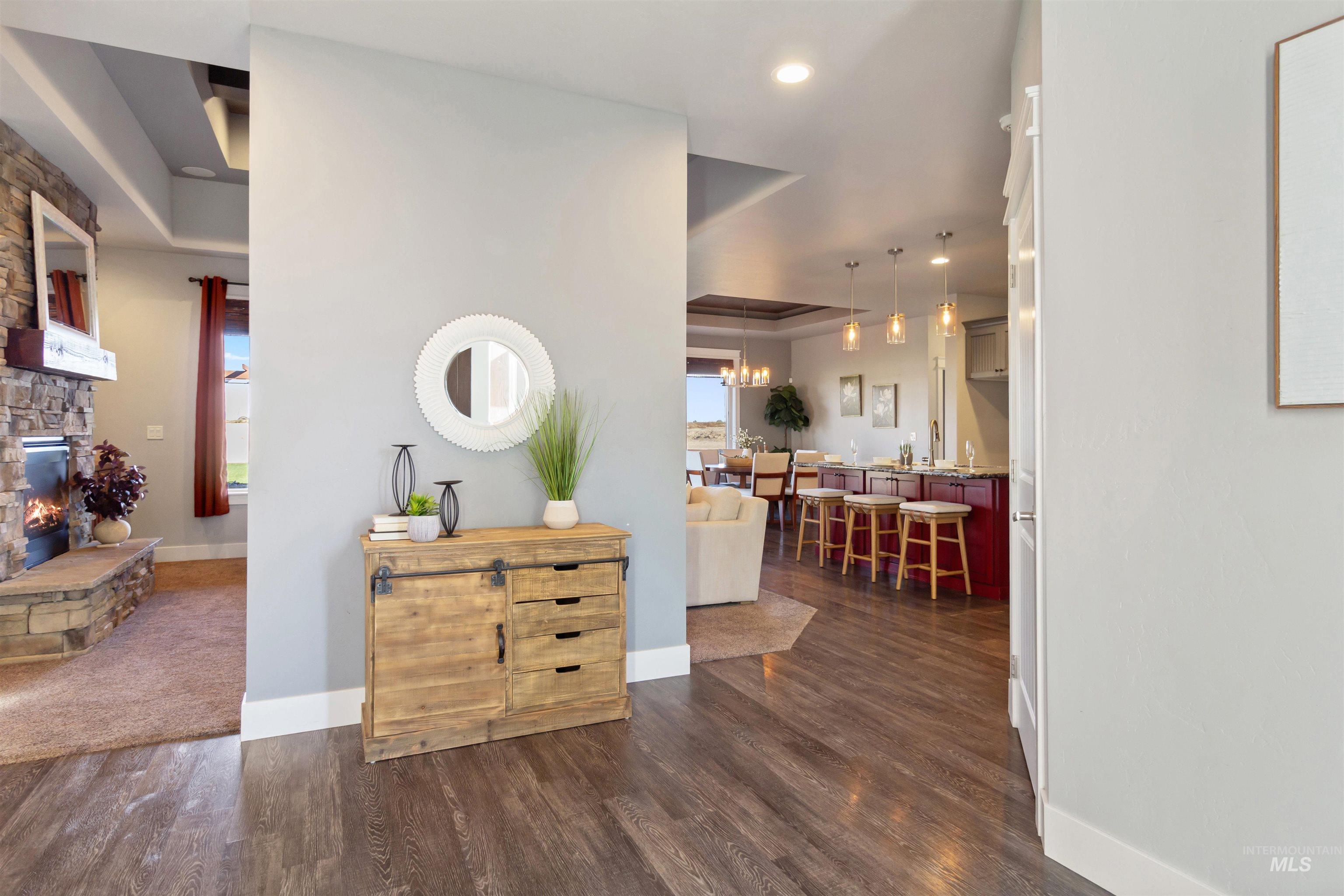 Hall featuring dark wood-style floors, a raised ceiling, and recessed lighting