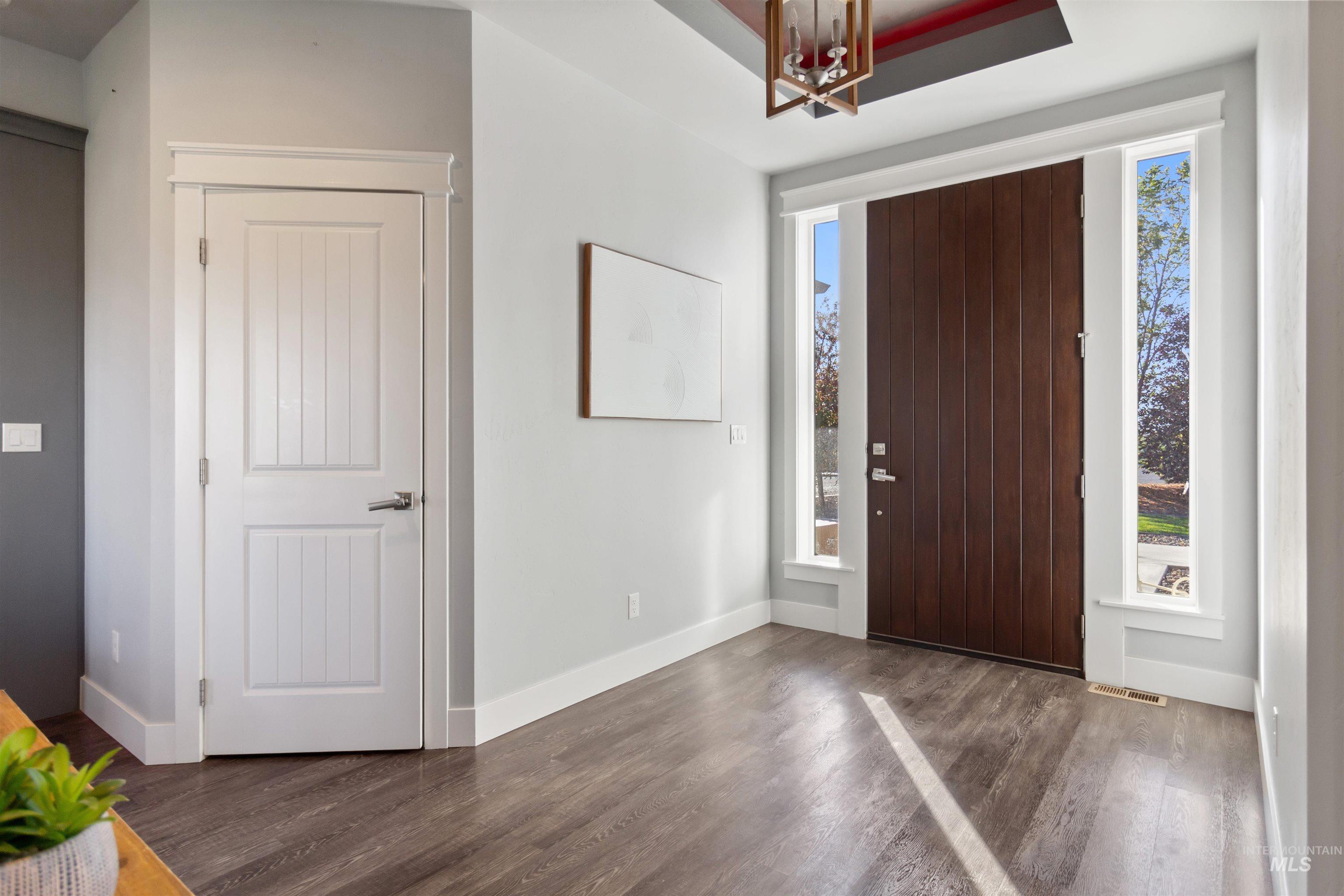 Entryway with dark wood-style floors and a chandelier