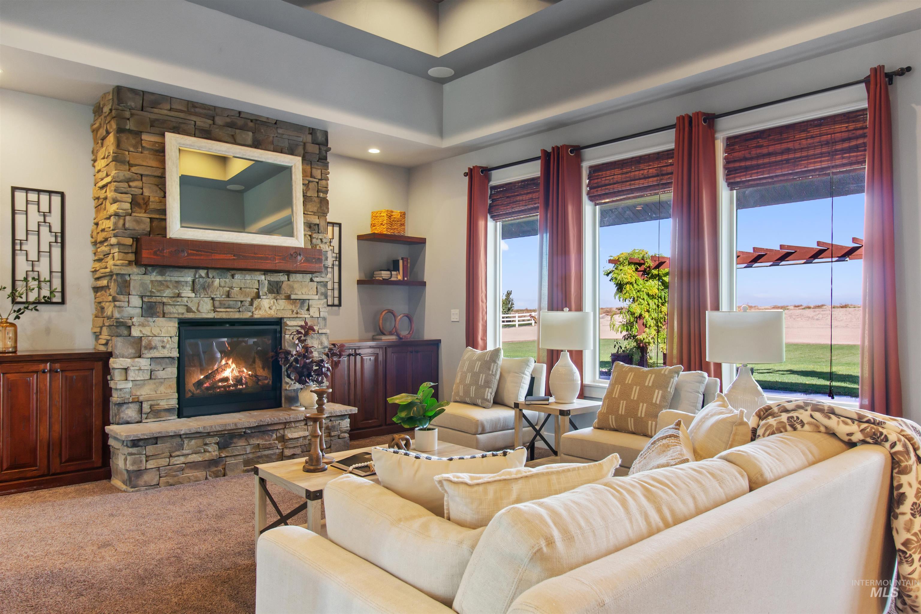 Carpeted living room with a stone fireplace and recessed lighting