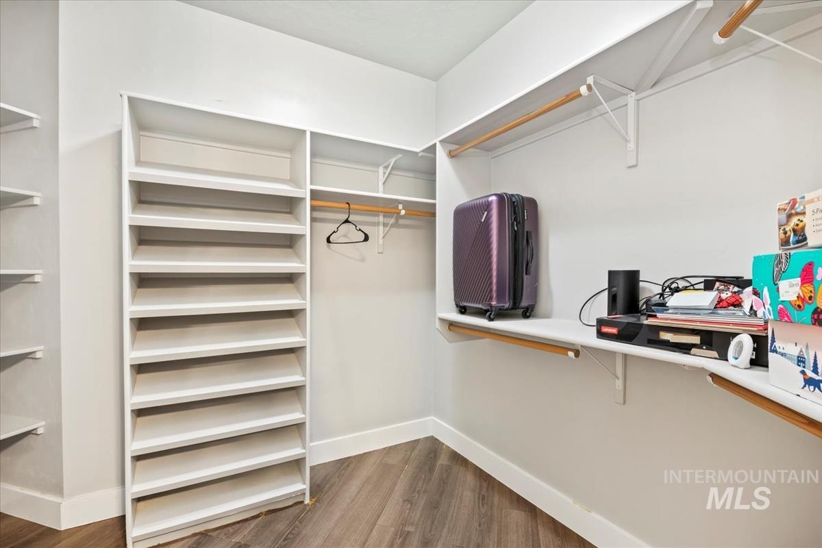 Walk in closet with dark wood-style flooring