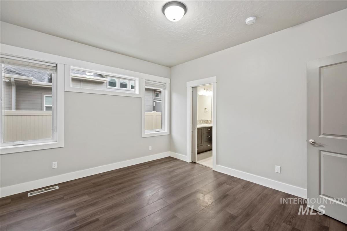 Unfurnished bedroom featuring dark wood-type flooring, a textured ceiling, and ensuite bathroom