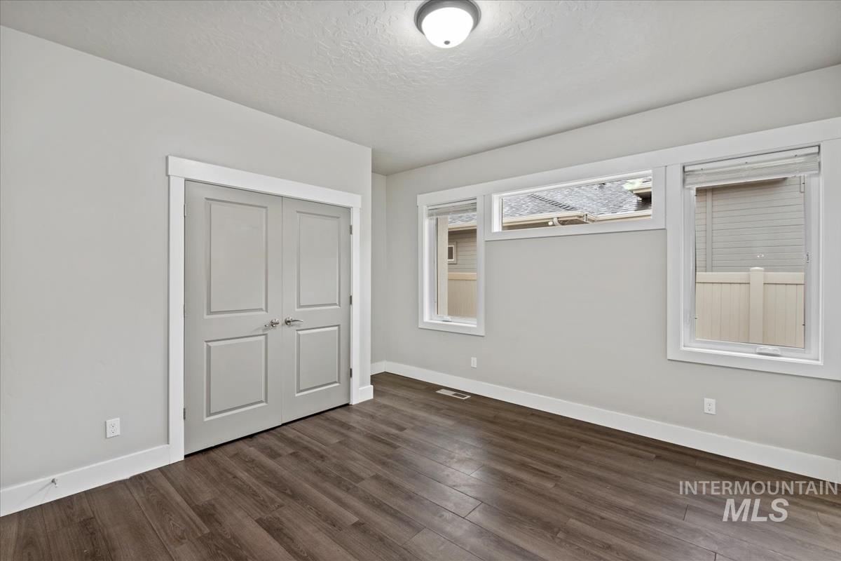 Unfurnished bedroom featuring dark wood-type flooring, a closet, and a textured ceiling