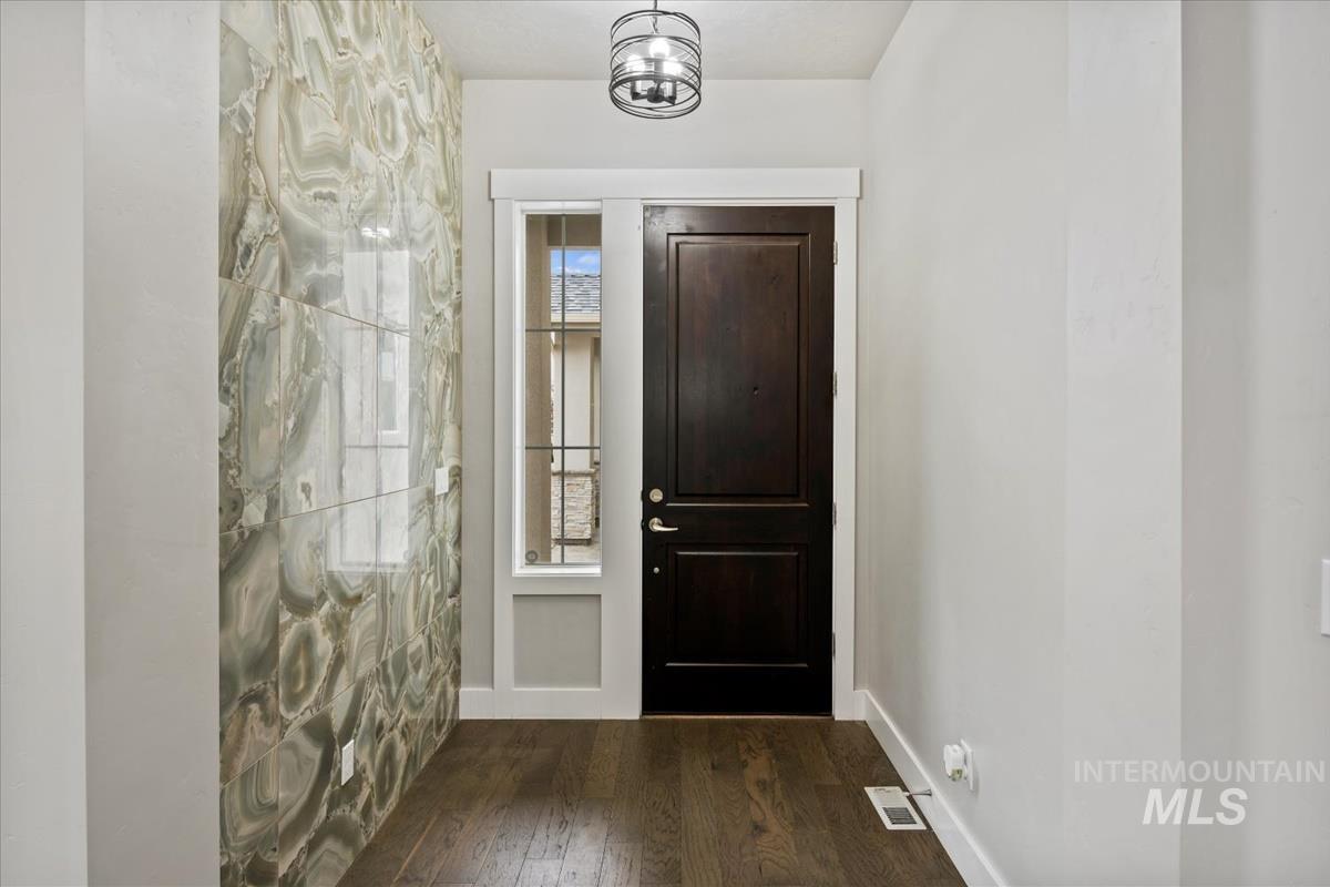 Foyer with dark wood-type flooring and baseboards