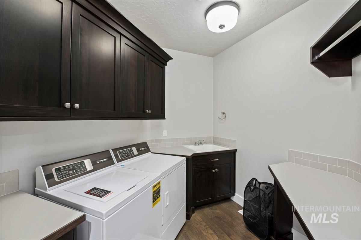 Washroom featuring dark wood-style flooring, a textured ceiling, washing machine and clothes dryer, and cabinet space