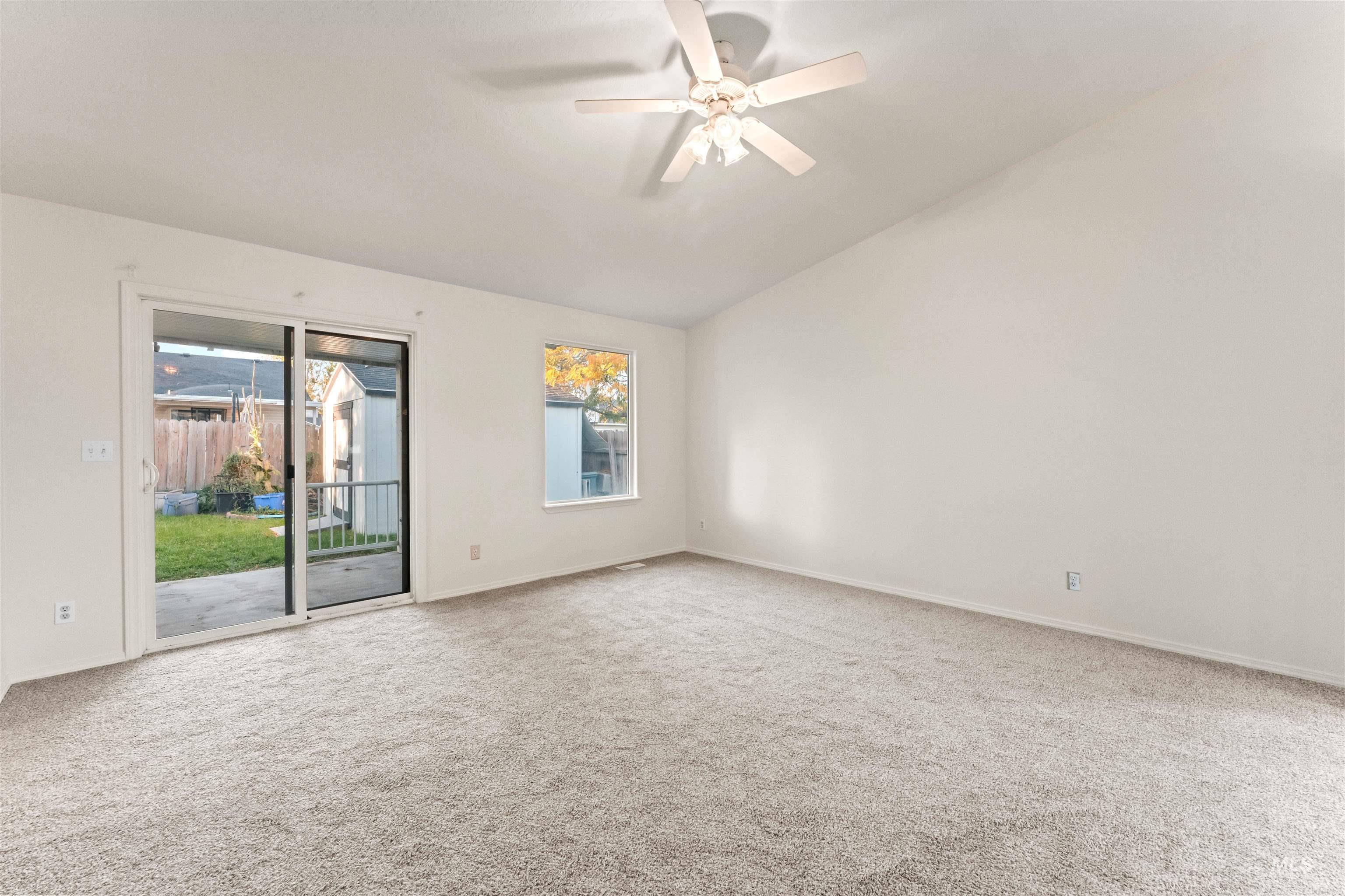 Spare room with vaulted ceiling, light carpet, and ceiling fan