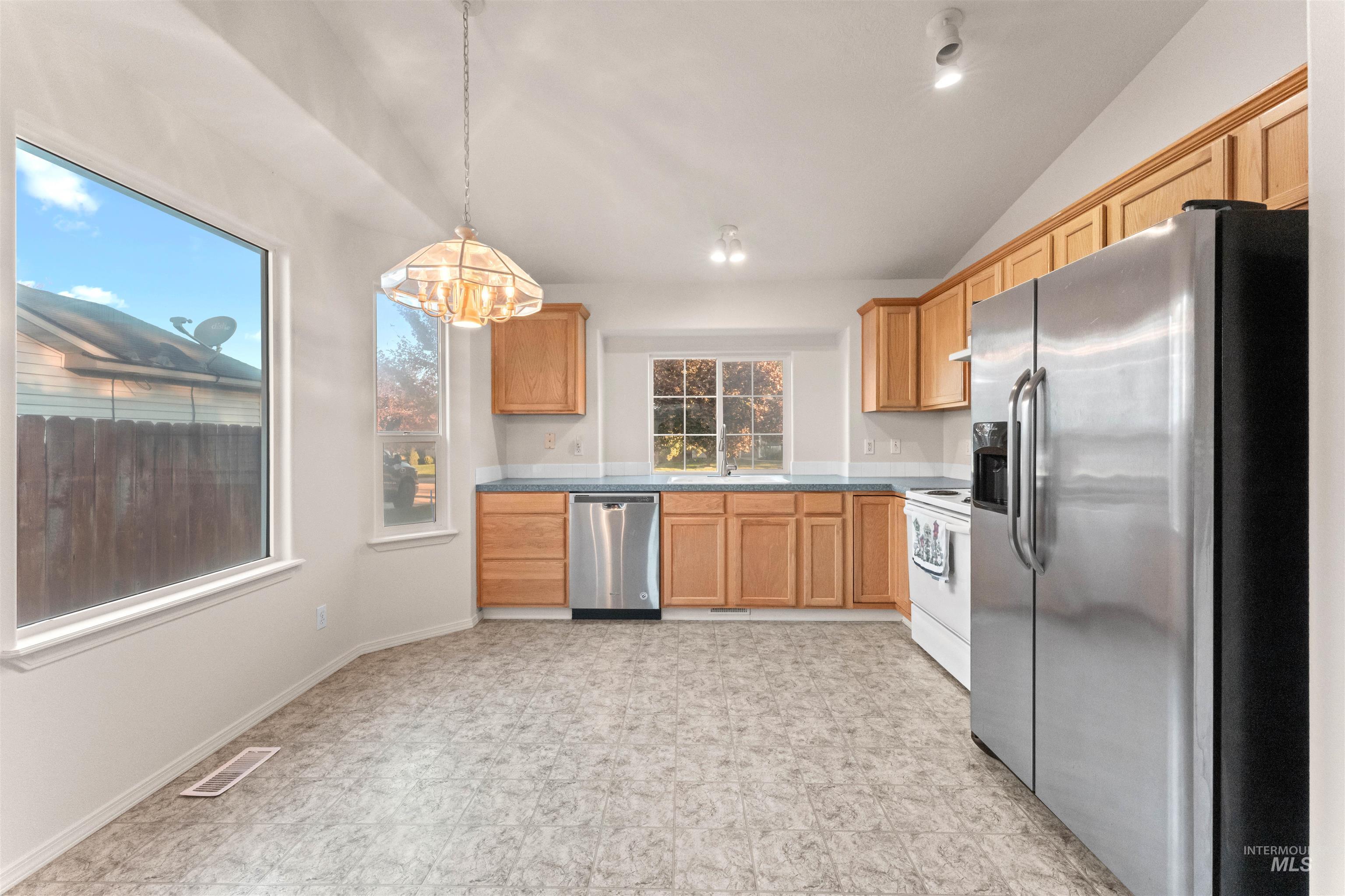 Kitchen with stainless steel appliances, hanging light fixtures, a chandelier, and lofted ceiling