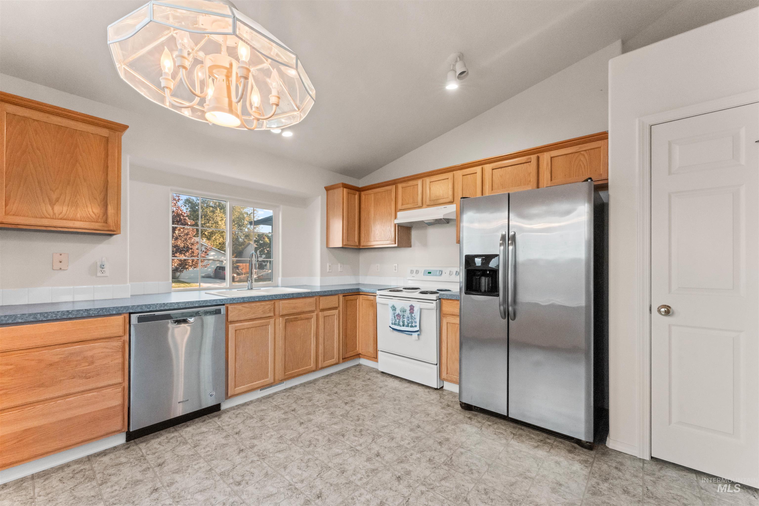 Kitchen with stainless steel appliances, lofted ceiling, pendant lighting, under cabinet range hood, and recessed lighting