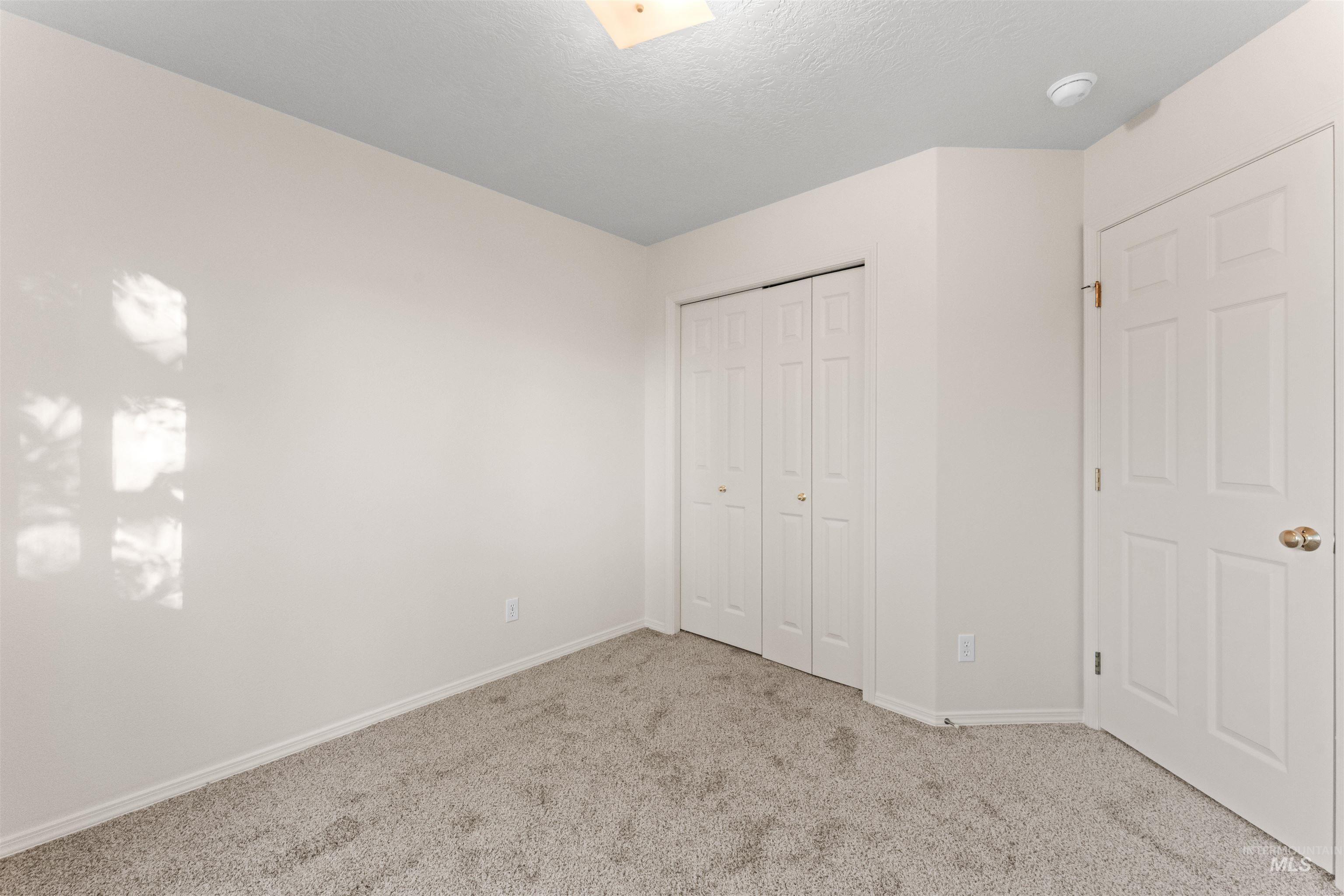 Unfurnished bedroom featuring light colored carpet, a closet, and a textured ceiling