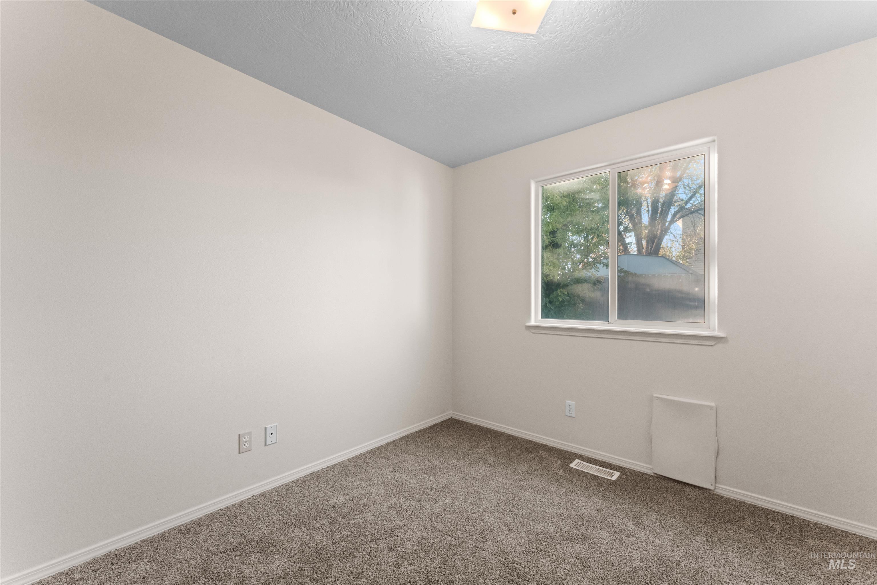 Carpeted spare room featuring baseboards and a textured ceiling