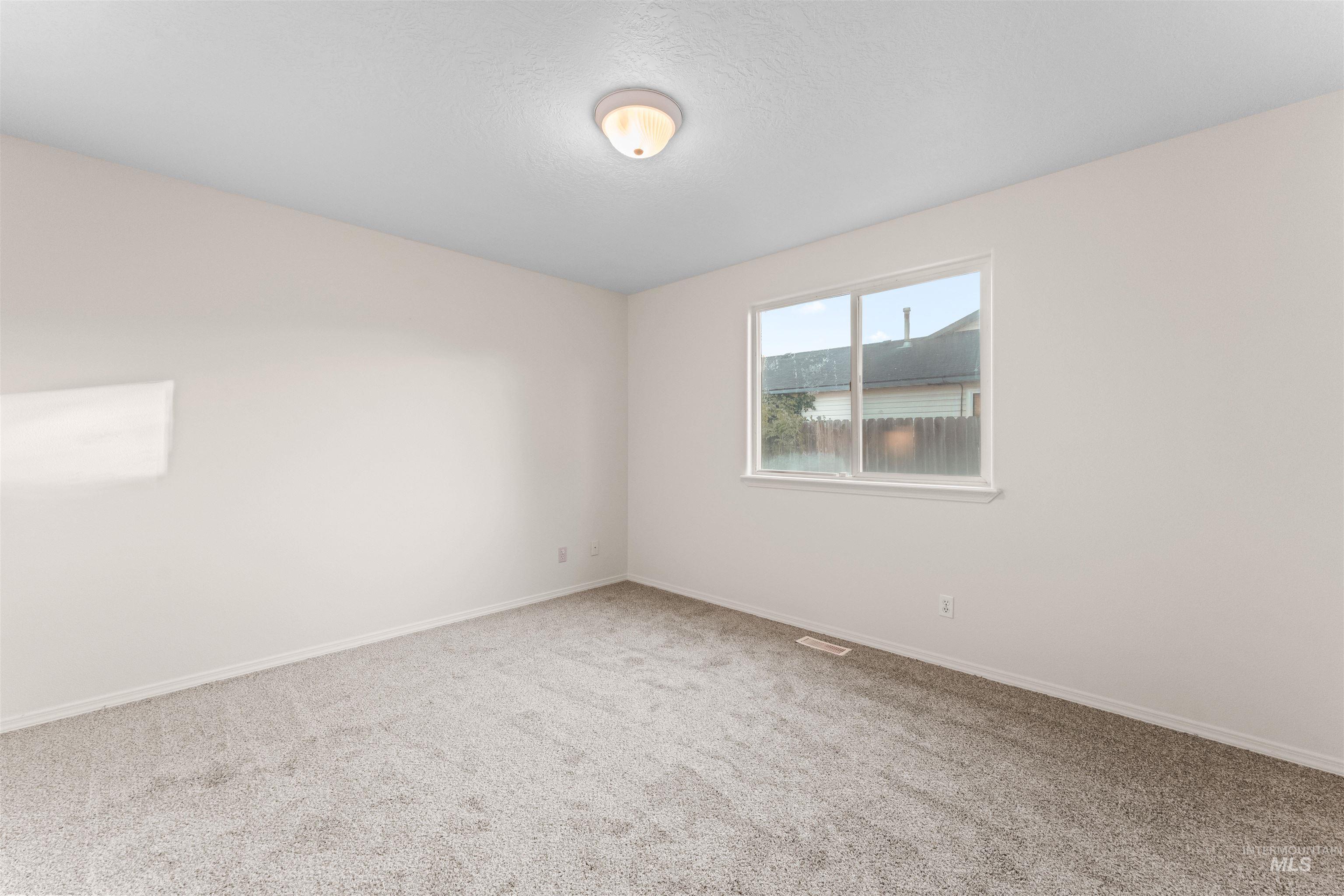 Spare room with light carpet and baseboards