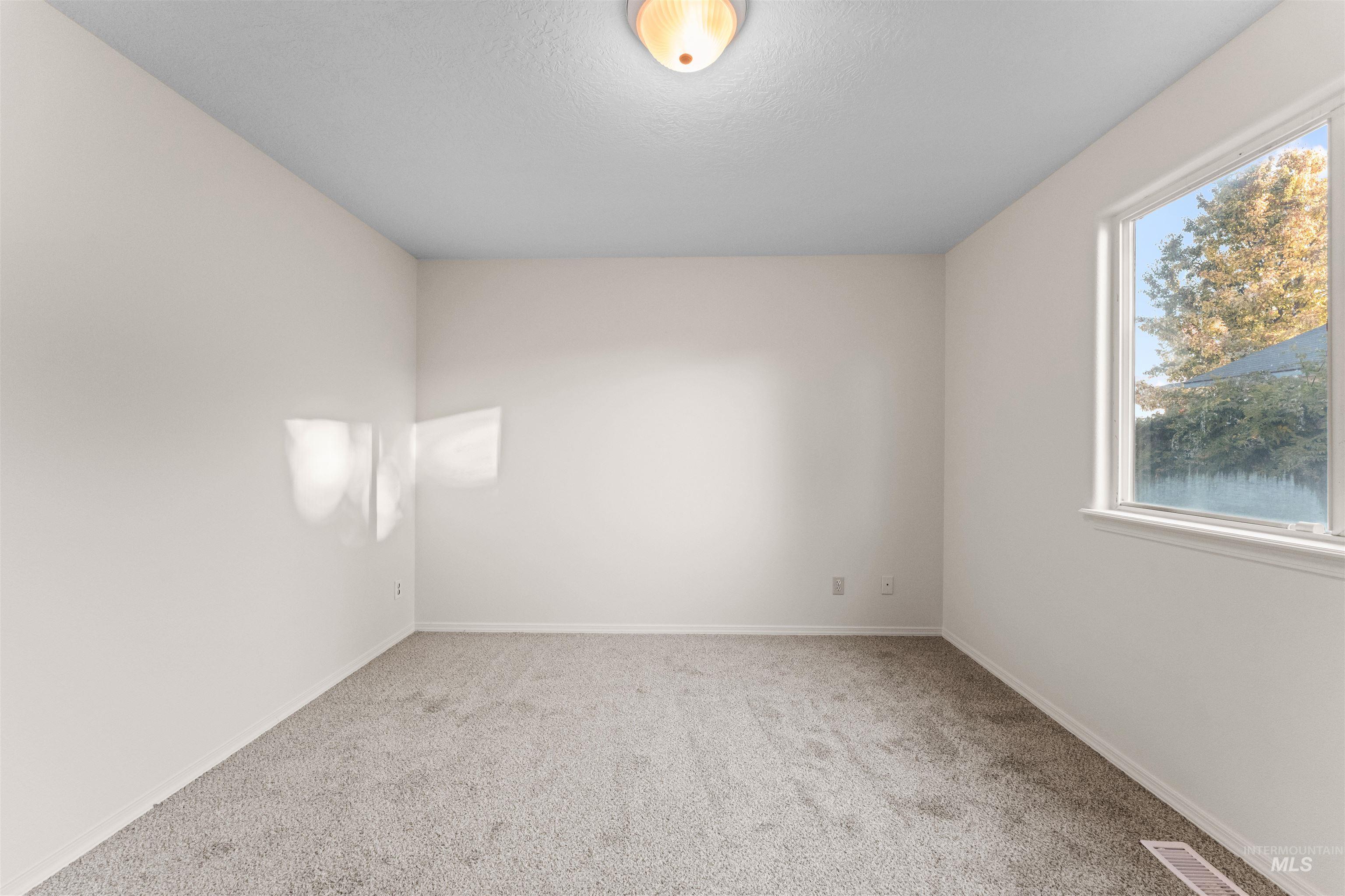 Unfurnished room featuring light carpet and baseboards