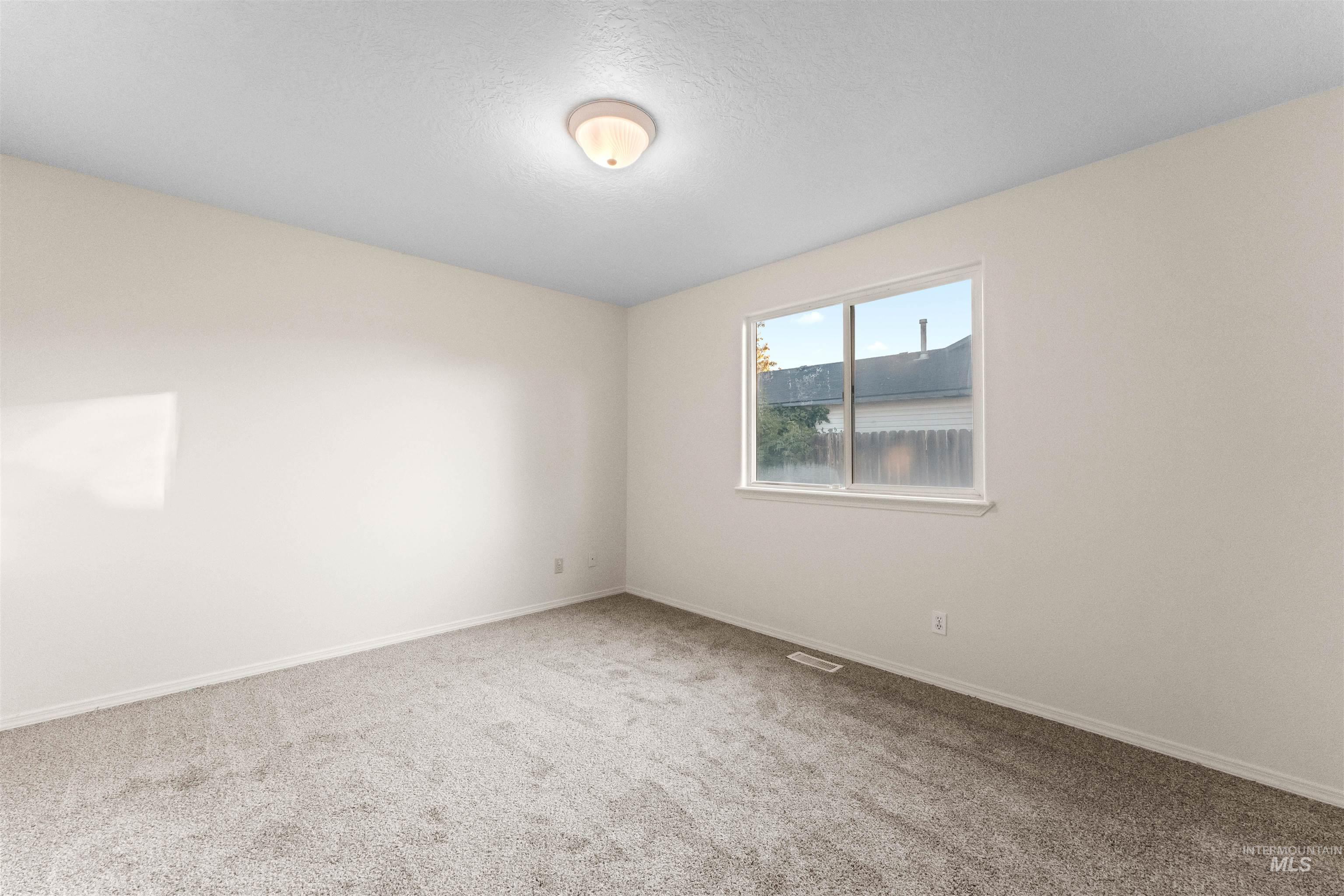 Spare room featuring light colored carpet and a textured ceiling