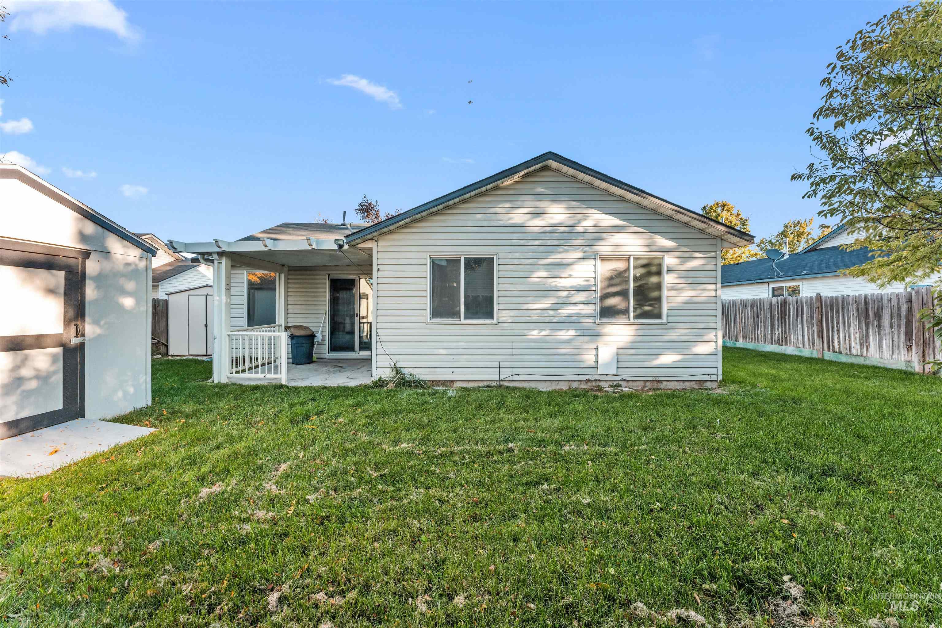 Rear view of house with a shed and a patio