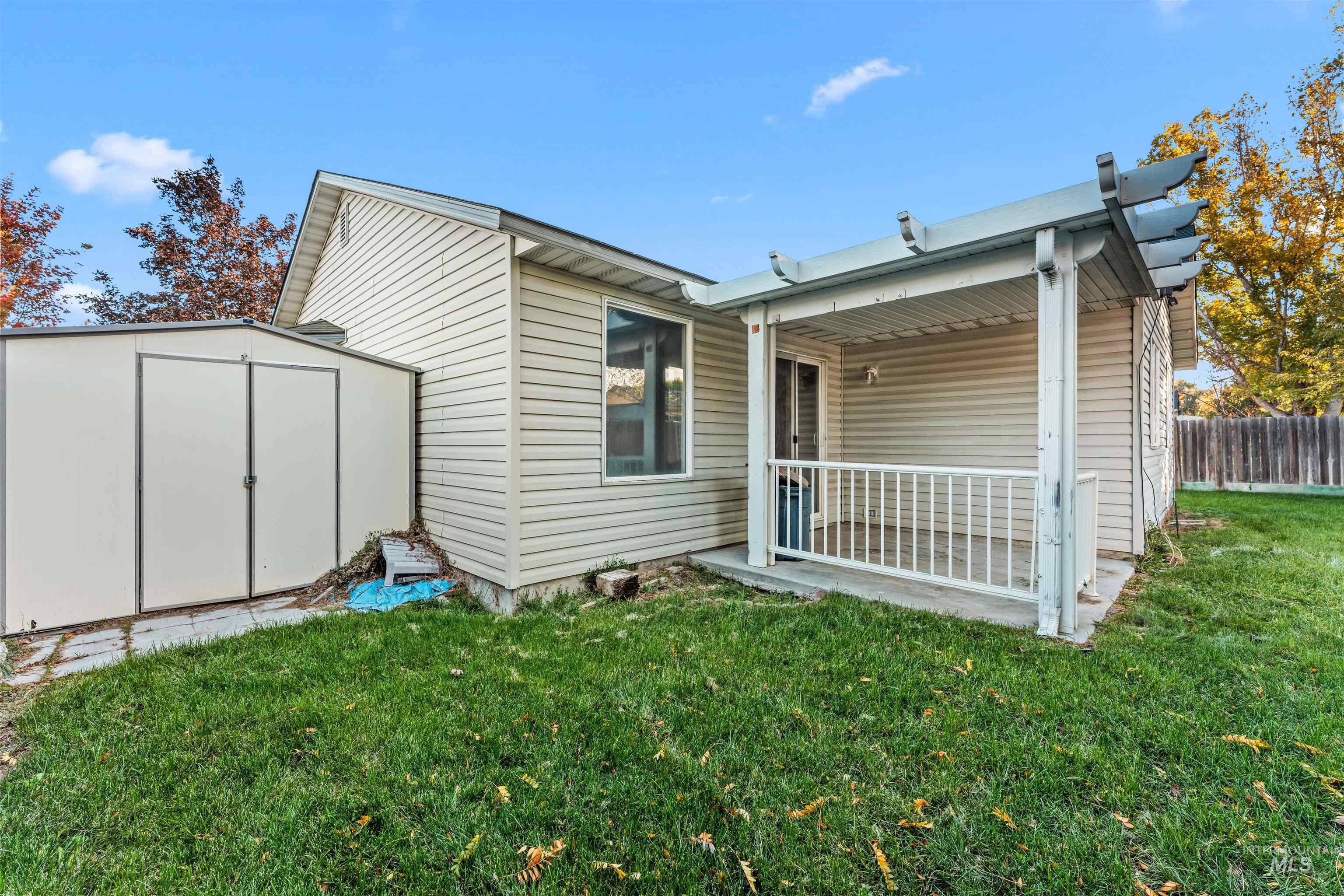 Back of house with a shed and a patio area
