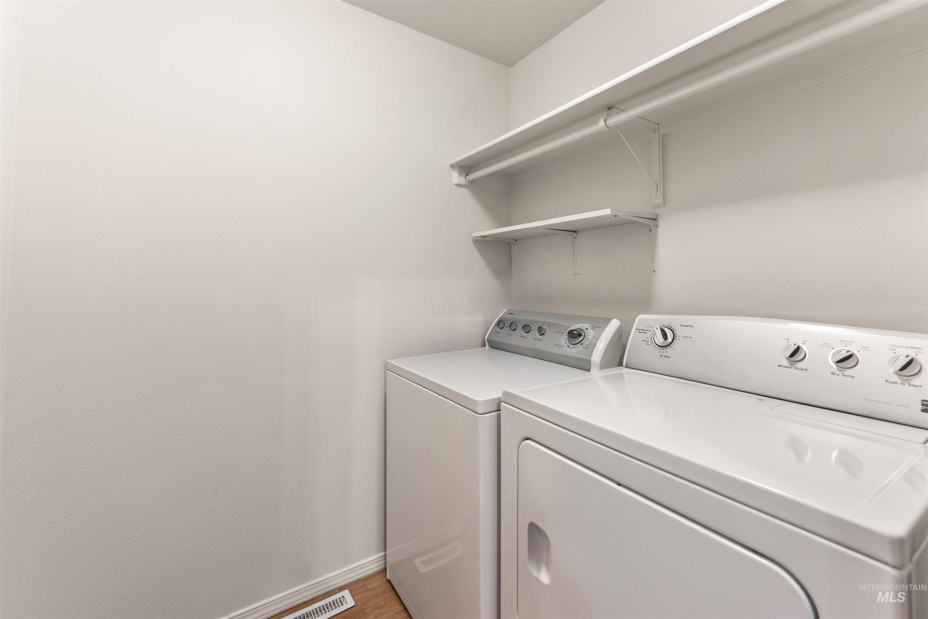 Laundry area with washing machine and clothes dryer and light wood-style floors