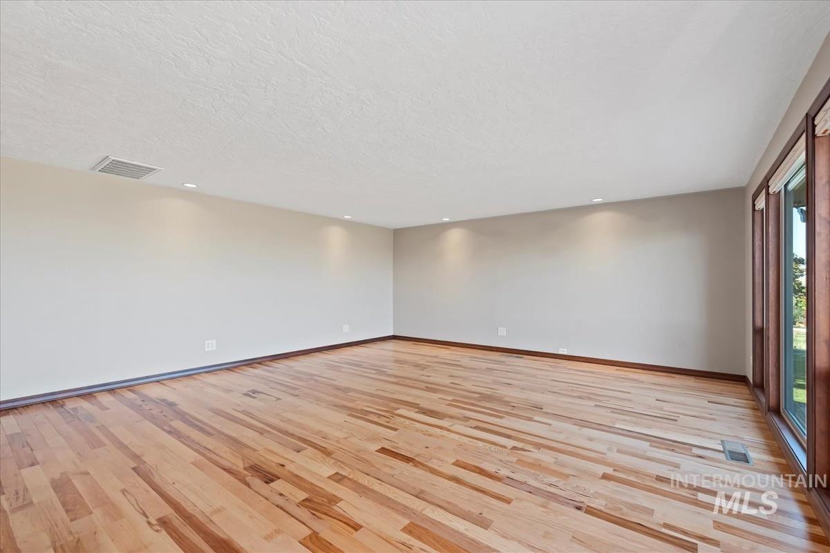 Unfurnished room featuring light wood-type flooring, a textured ceiling, and recessed lighting