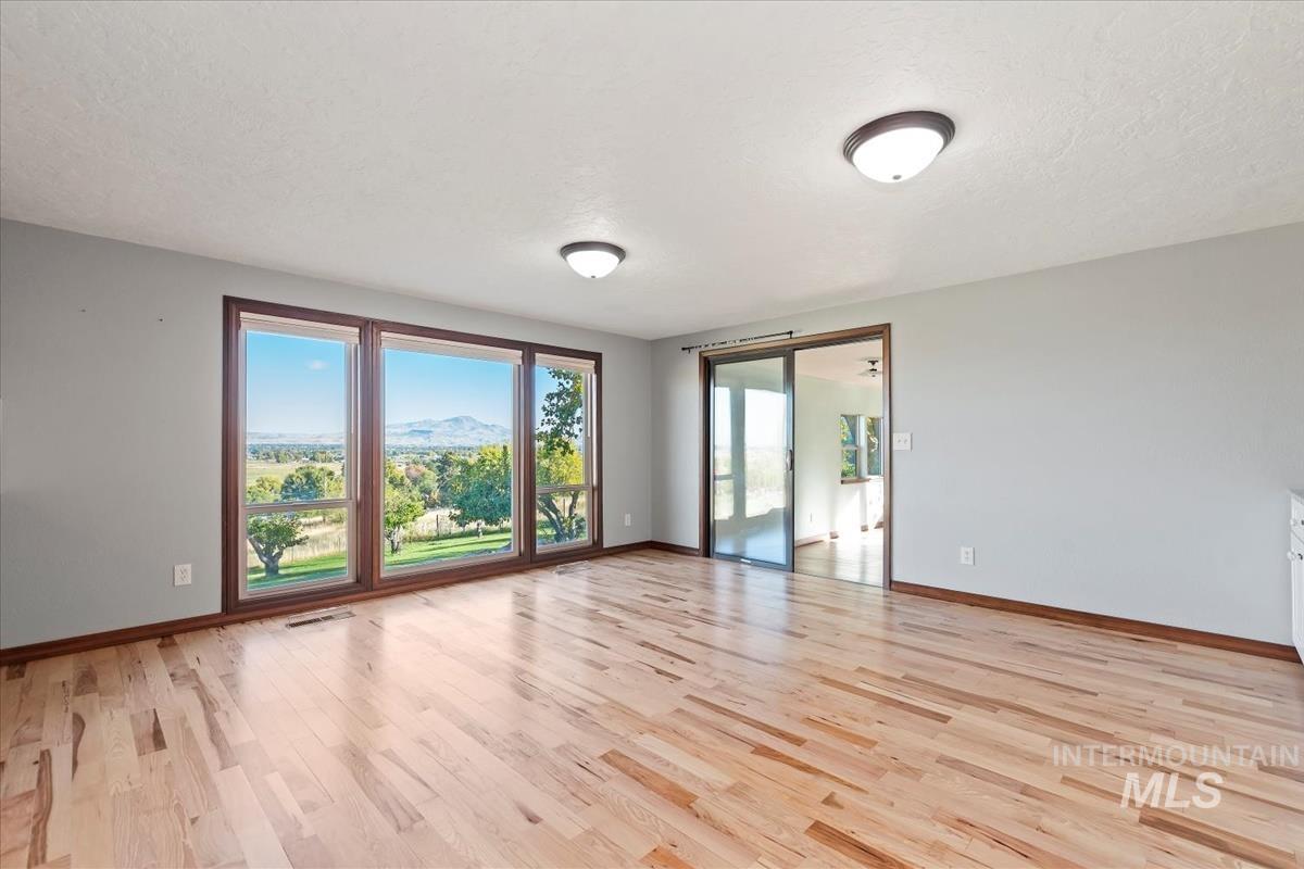 Unfurnished room featuring light wood-type flooring, a textured ceiling, and a mountain view