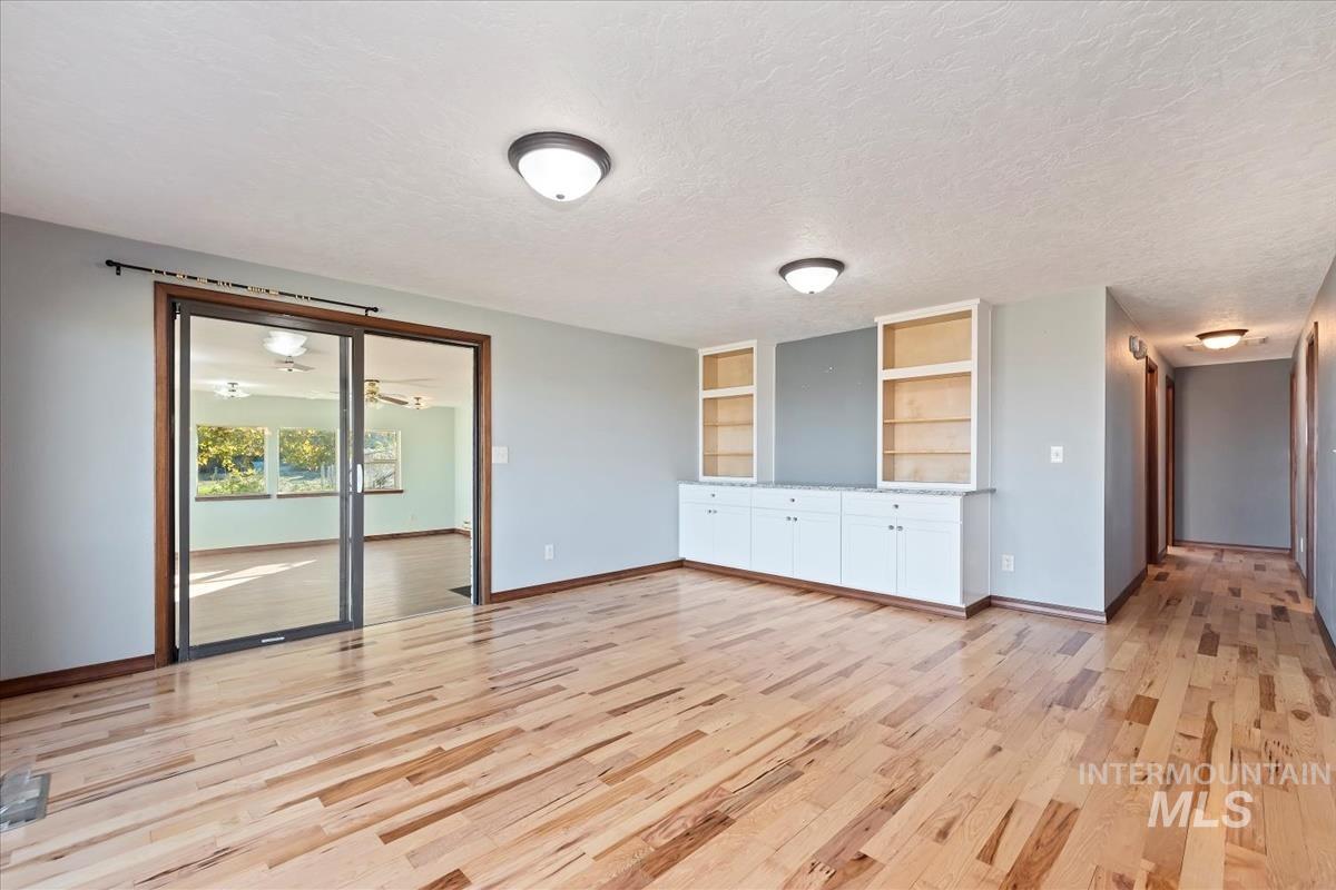 Unfurnished living room with built in features, light wood finished floors, and a textured ceiling