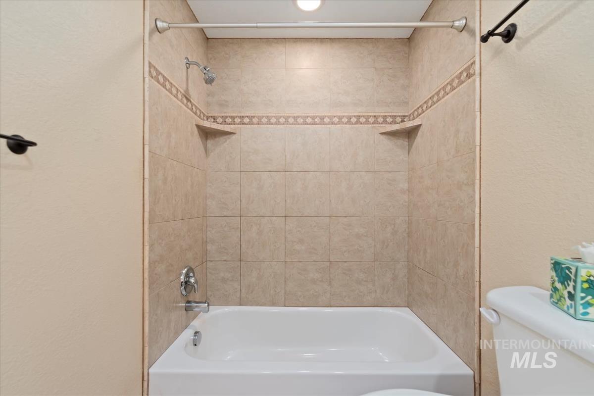 Full bath with shower / tub combination and a textured wall
