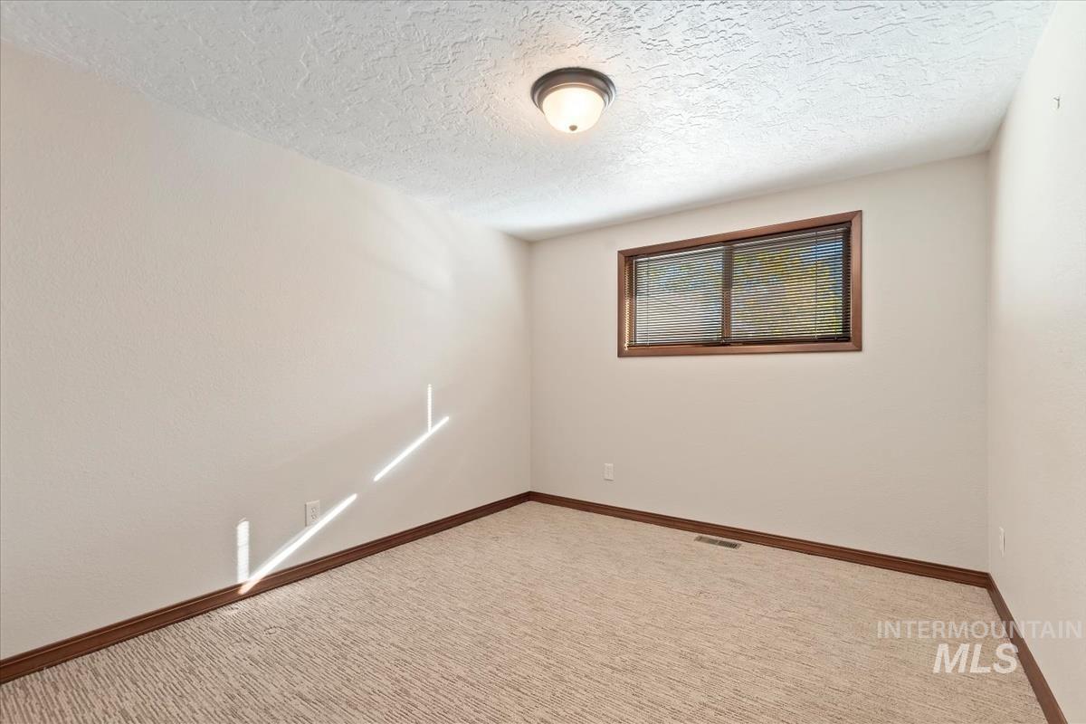 Carpeted spare room with baseboards and a textured ceiling