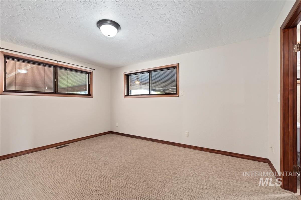 Empty room featuring a textured ceiling and light colored carpet